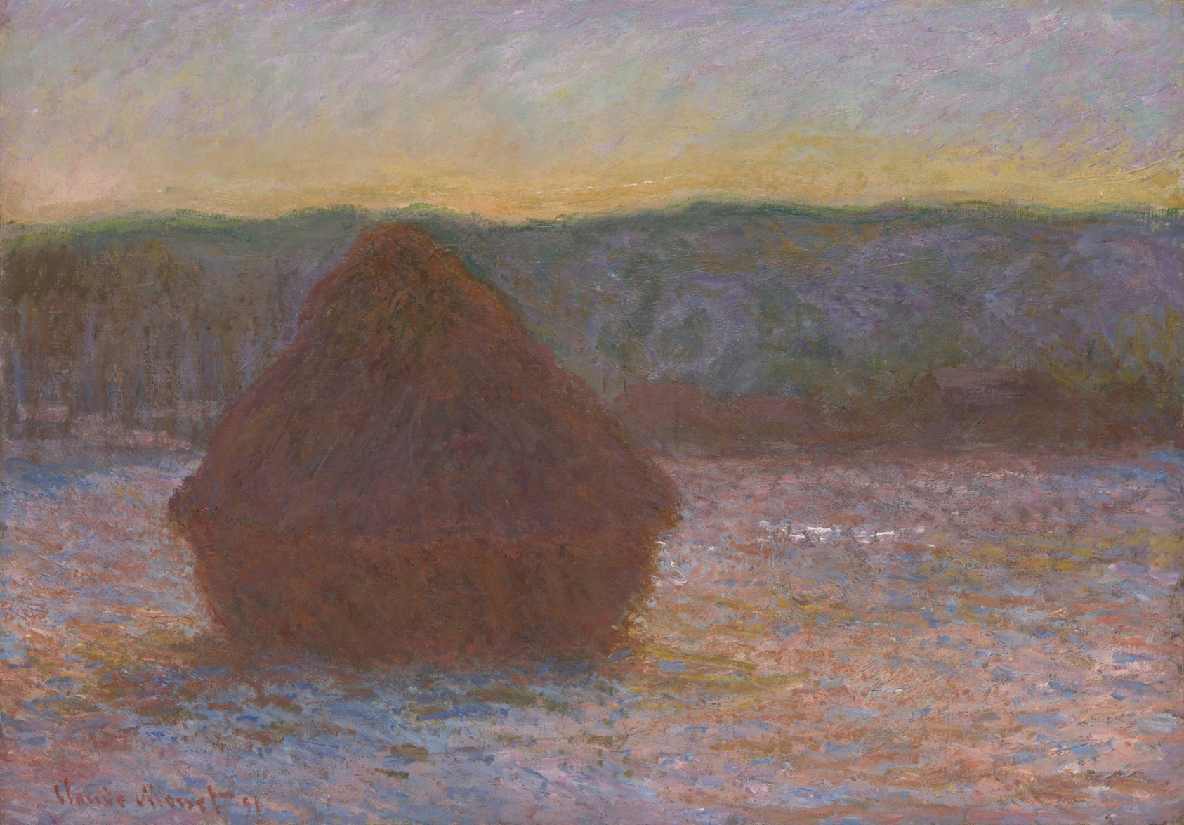 A lone wheat stack, in shadow, rests on a field with traces of snow, the snow taking on reflected shades of pink, yellow, orange, and blue from the unseen setting sun. A line of pale yellow illuminates the horizon above the hills beyond.