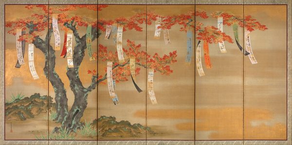 Papers with Japanese text hang from a tree bearing red and gold leaves.