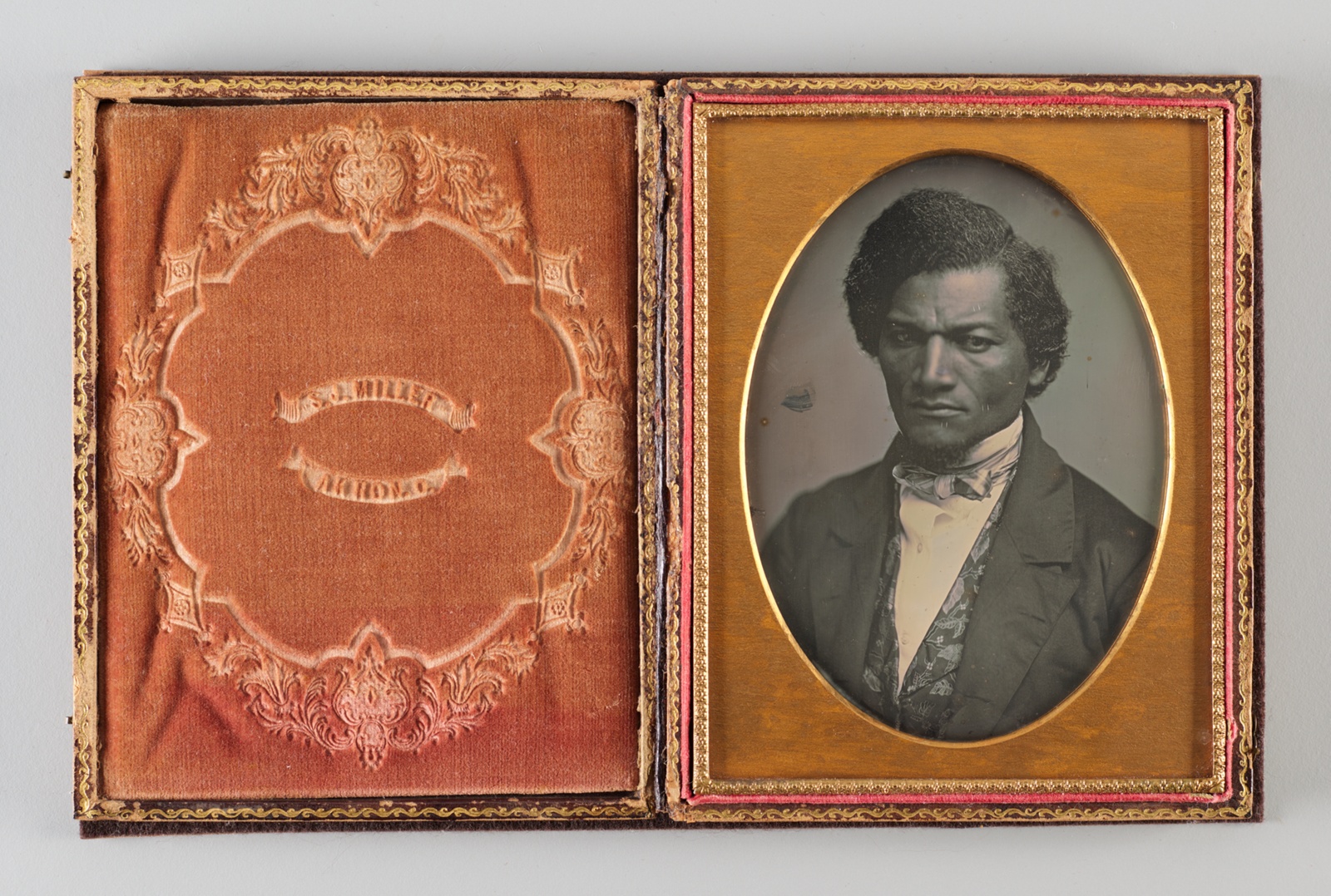 Historical black and white photographical portrait of Black man in a suit, gold frame.