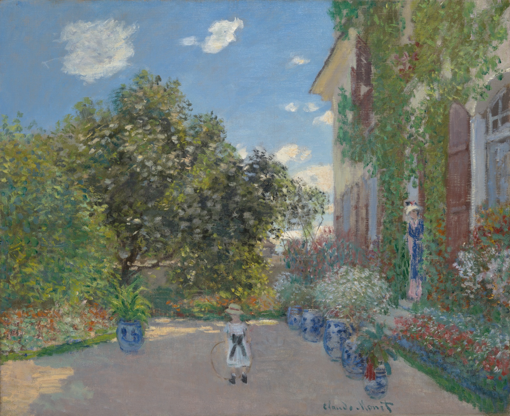 Among potted flowers and lush foliage, a tiny child in a white dress plays with a hoop. A woman peers at the child from an ivy-covered building at right.