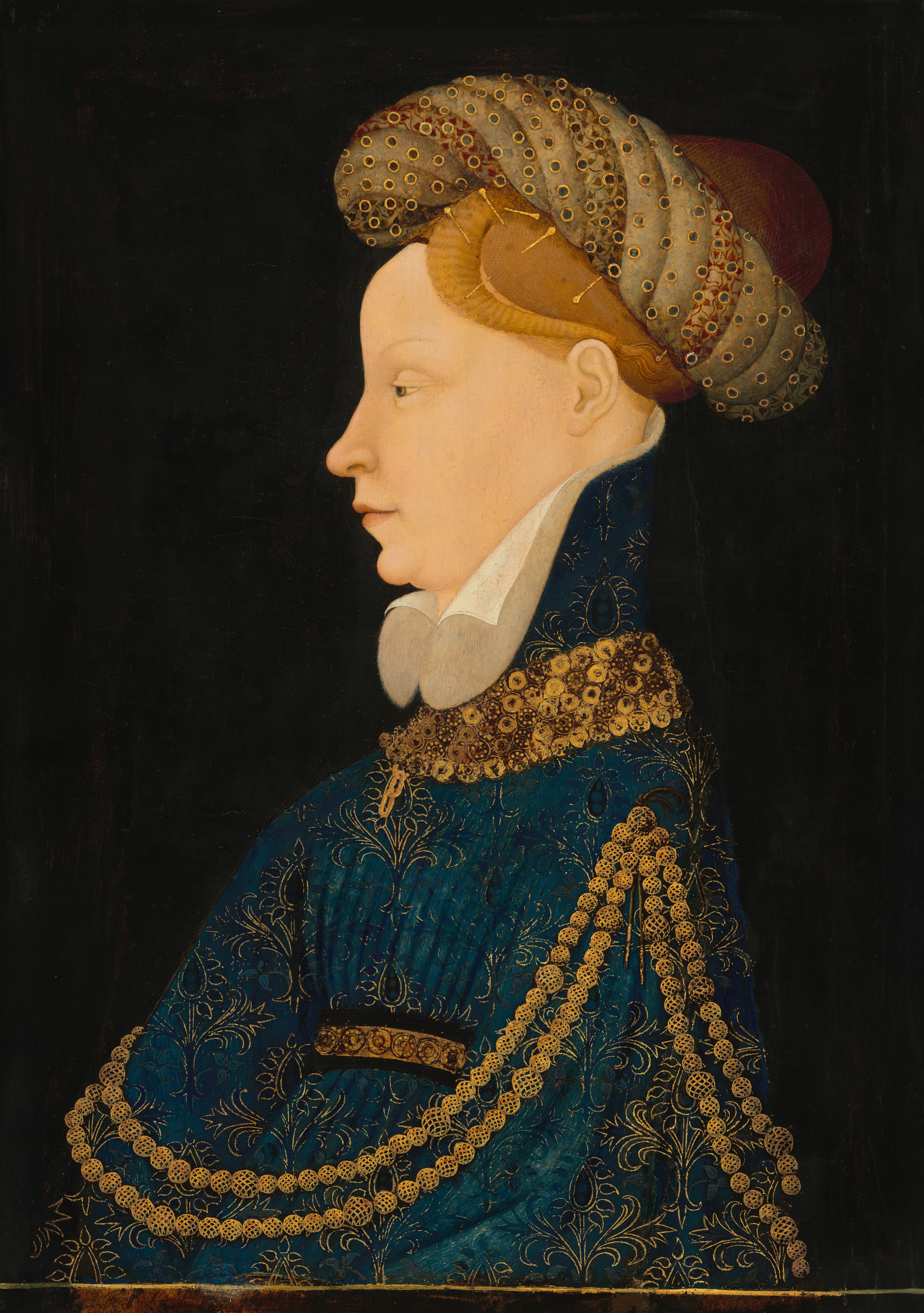 Shown from the chest up on the far side of a narrow ledge, a woman wearing an elaborate headdress and gown faces our left in profile in this vertical portrait painting. Her pale-peach skin is smooth with little shading around the features. The hazel eye we see is heavy-lidded under a thin, arched brow. The woman has a notably high forehead and a sloped nose. Her lips are closed over a knobby chin and fleshy jawline. Her hair is gathered up in a fine gold net under a twisted, ring-like headdress held in place with long gold pins. The fabric of the headdress alternates between twists of parchment brown or light brown patterned with red or darker brown leaf patterns. A network of muted blue dots encircled with gold does not quite line up with the headdress it overlays. The high collar of the woman’s peacock-blue dress flares up the back of her head over a white collar that curls away along either side of her chin. The garment is covered with flowers and stems outlined in gold. There are thick gold bands at her neck and around her waist. A chain made up of two strands of gold orbs like oversized beads hangs from the shoulder closer to us and then wraps around her body. A gold pendant near her neck may be two chain links or a thin letter B. Light glints off the ledge along the bottom of the painting, and the background is inky black.