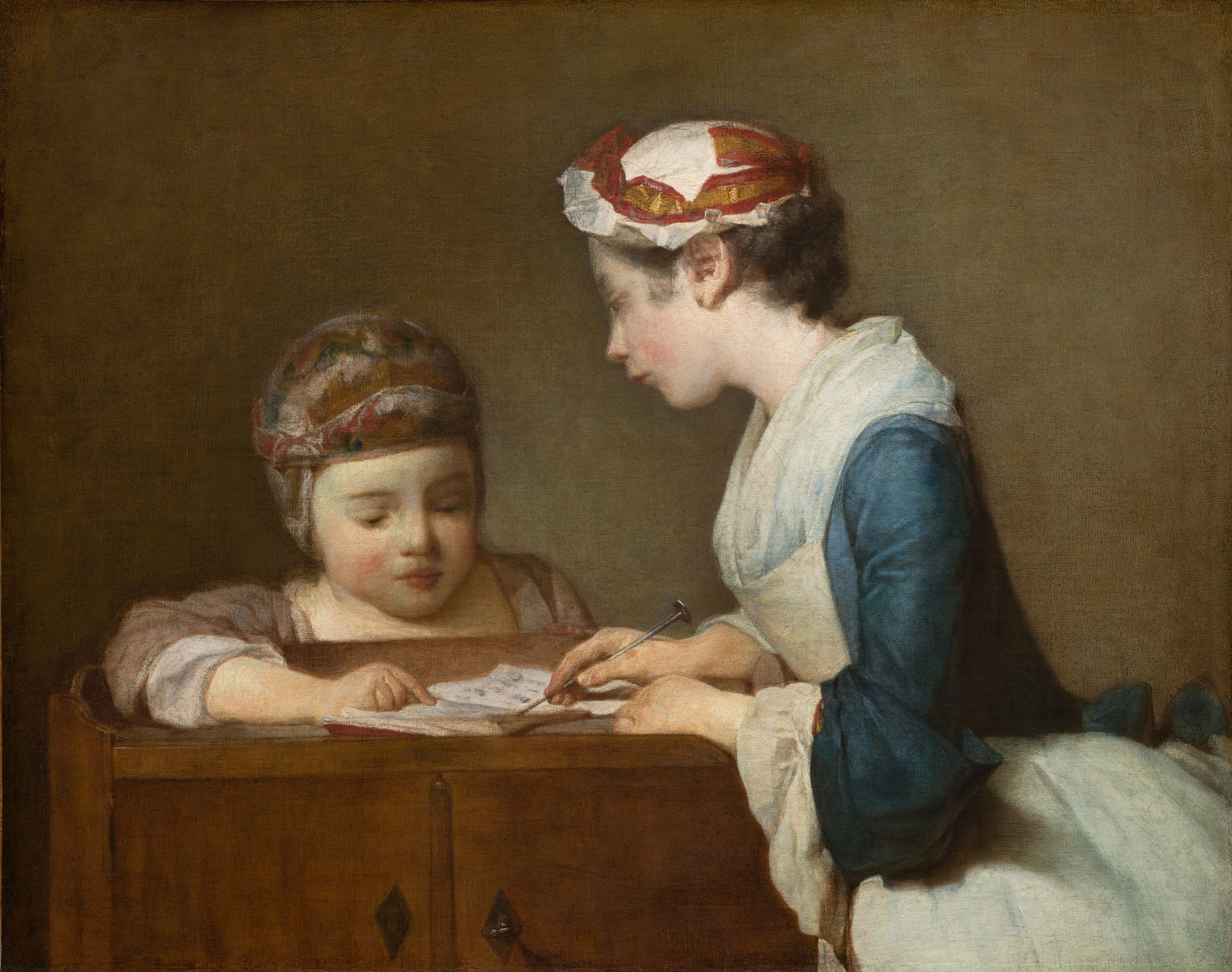 An older girl and a younger child, both with pale skin, bend toward each other as they look at a book spread open on a wooden cupboard in this nearly square painting. Shown from the hips up to our right, the girl leans over the cupboard with her body facing our left in profile. She looks at the child peering over the low ledge at the back of the cupboard with her head tilted slightly in that direction. The older girl has a straight, delicate nose, her smooth cheeks are flushed, and her rosy-red lips are pursed. Her brown hair is tucked under a bright white, ruffled cap encircled with a gold and cranberry-red ribbon. The long sleeves of the muted sapphire-blue dress seem to have been rolled back along the forearms to reveal cascading, white cuffs. A translucent white neckerchief, like a short, full scarf, is tucked into an ivory-white apron that also covers the flaring skirt. With both hands on the open book, she points to one page with a metal pointer like a knitting needle. Facing us, the smaller child looks at the book from behind the wood cupboard, eyes downcast, resting one forearm on the surface and pointing to a detail in the book. The child has delicate brows, a short, wide nose, and full raspberry-red lips are closed. The padded cap the child wears covers the ears and is loosely painted with a pattern of honey brown, silvery white, and slate blue. The nutmeg-brown sleeves are pushed back along the forearm and there are white cuffs or sleeves beneath. The cupboard has two diamond-shaped, iron-gray metal pulls in front. Light illuminating the pair from our left creates a greenish glow on the tawny-brown background behind them.