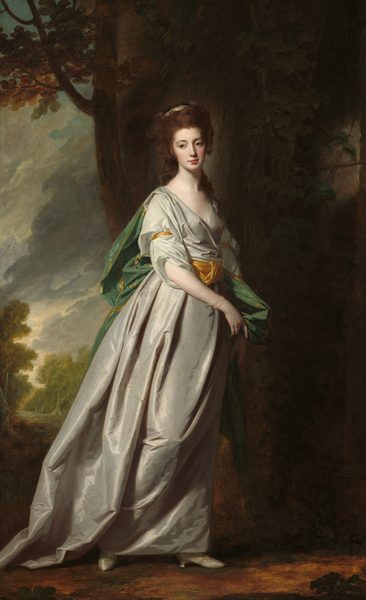 A young woman with smooth, pale skin wearing a fog-gray gown stands in shadowy outdoor setting in this vertical portrait painting. Her body faces our right almost in profile. Her head turns toward us though she looks off to our left with brown eyes under arched brows. Auburn-brown hair frames her heart-shaped face, which has a slender nose over closed, coral-red lips and a dimpled chin. Her long, curly hair is gathered at the back of her head and tied with a sand-brown ribbon. Long tendrils hang down her shoulders and back. Her iridescent gown has a deep neckline and a wide, harvest-gold sash around her waist with matching bands on the upper arms. A shimmering, laurel-green cape bordered in gold falls from her shoulders in deep folds down her back. The woman has pulled some of the cape forward with both hands to hang down her left side, farther from us. She wears delicate, translucent pearl bracelets on one wrist, and steps forward on silvery-gray shoes under the dress’s long hem. Bright light falls across the scene from the upper left so much of the background is in shadow. A stone wall behind the woman spans the right half of the painting. A tree grows up along its leftmost edge, just beyond the woman’s shoulders. A landscape along the left third of the composition opens onto trees under a sky filled with thick, off-white and steel-gray clouds.