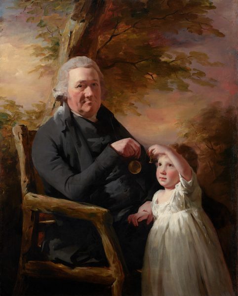 Shown from the knees up, an older man sits in a rustic wooden chair and holds up a pocket watch for a young child who stands at his knees in this vertical portrait painting. They both have pale, peachy skin with flushed cheeks. They are lit from our upper left so the man’s face is partly in shadow while light pours onto the child’s upturned face. The man’s body is angled to our right, almost in profile, but he turns his head to look at us with dark eyes under heavy brows. His has a bulbous nose, lined cheeks, and a heavy jowl around thin lips, which are closed in a line. His light gray, wavy hair is tied back at the nape of his neck. He wears a black coat with a high collar and tightly fitting sleeves. A streak of white at his neck suggests a white shirt under the black, high-necked vest that covers his torso. He rests his right elbow, closer to us, on the arm of the chair so he can dangle a pocket watch in front of the child. The man’s knees disappear behind the child, who leans against his legs. The pocket watch is attached to a short gold chain, and the child holds up the fob, which is shaped like a Hershey’s Kiss candy, at the end of the chain. The young boy looks up at the watch with luminous, brown eyes. He has smooth, round cheeks, a short nose, and his pink lips are closed. The child has wavy, golden brown hair and his white garment has a squared neckline, short sleeves, and falls like a skirt off the bottom edge of the painting. The background behind the pair is painted with streaks of marigold orange, gold, and olive green to suggest trees against a sky painted with butter and harvest yellow, rust orange, and just a touch of pale blue at the upper left corner. The entire portrait is loosely painted, especially in the background, chair, and clothing.