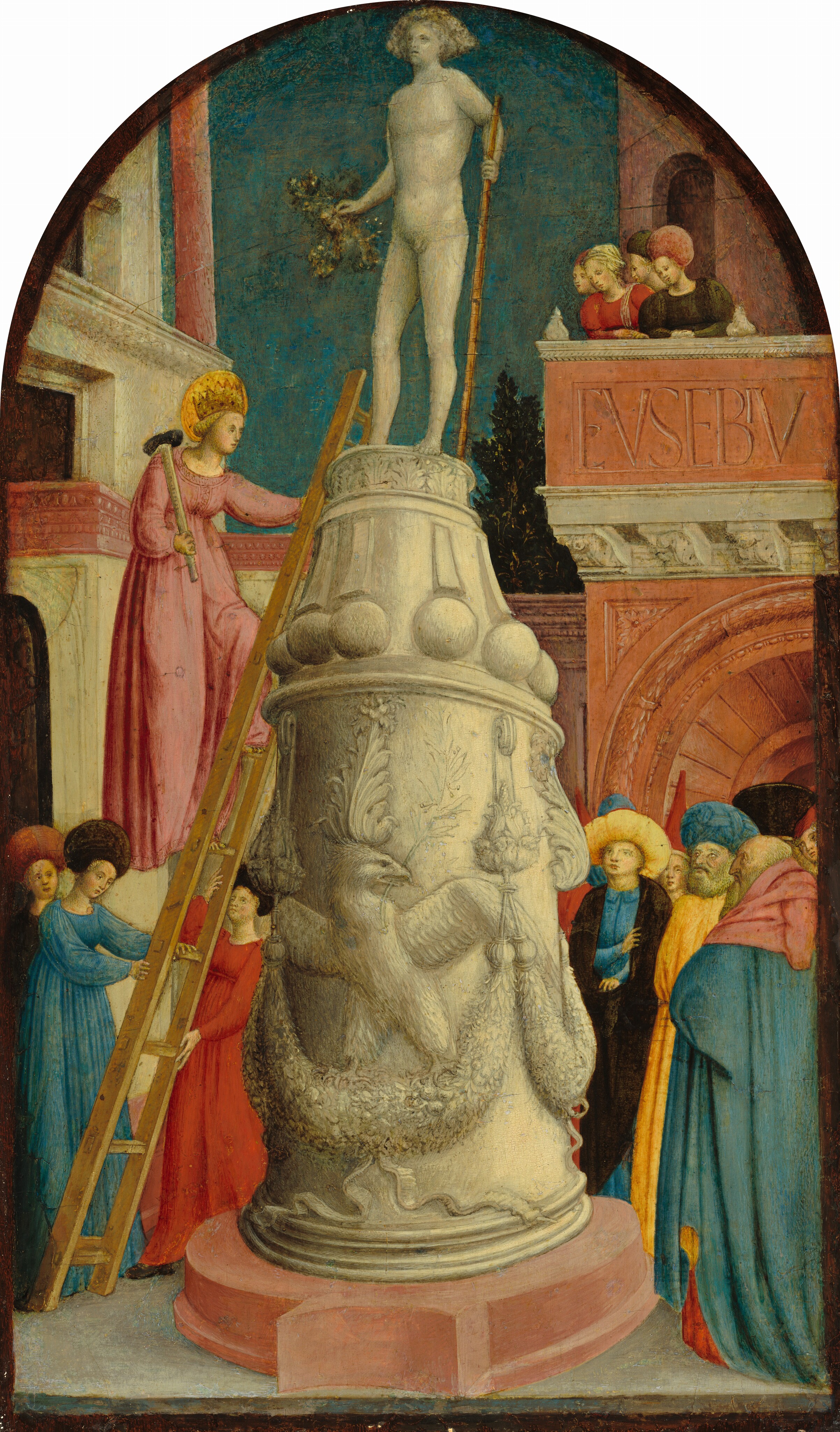A woman climbs a ladder propped against a tall base of a white stone sculpture with a sledgehammer over one shoulder in this vertical, arched painting. The statue stands in a narrow town square hemmed in with buildings on each side. About a dozen people look on from the ground and from a balcony to our right. All the people have pale skin and wear dresses, robes, or cloaks in topaz blue, red, harvest yellow, or black. The base of the statue is twice as tall as any of the onlookers, and the statue atop is life sized. The base has eagles standing astride garlands, with flame-like leaves flaring above their heads. The statue is of a nude male with chin-length hair. He holds a gold staff in one hand and what appears to be a branch in the other. The woman climbing the ladder wears a carnation-pink dress, a gold crown, and has a gold, disk-like halo. Two more women brace the foot of the ladder, and another stands nearby. The three-story building behind them has a white façade with a carved, pink entablature across the top of the first level. More women and men gather to our right in front of a terracotta-orange building with a wide, arch opening on the ground level. Four women look down from a balcony on the second level. The face of that building is carved over the door to read, “EVSEBIV.” A tree grows beyond an enclosing wall at the far side of the square, between the buildings, beneath an azure-blue sky.