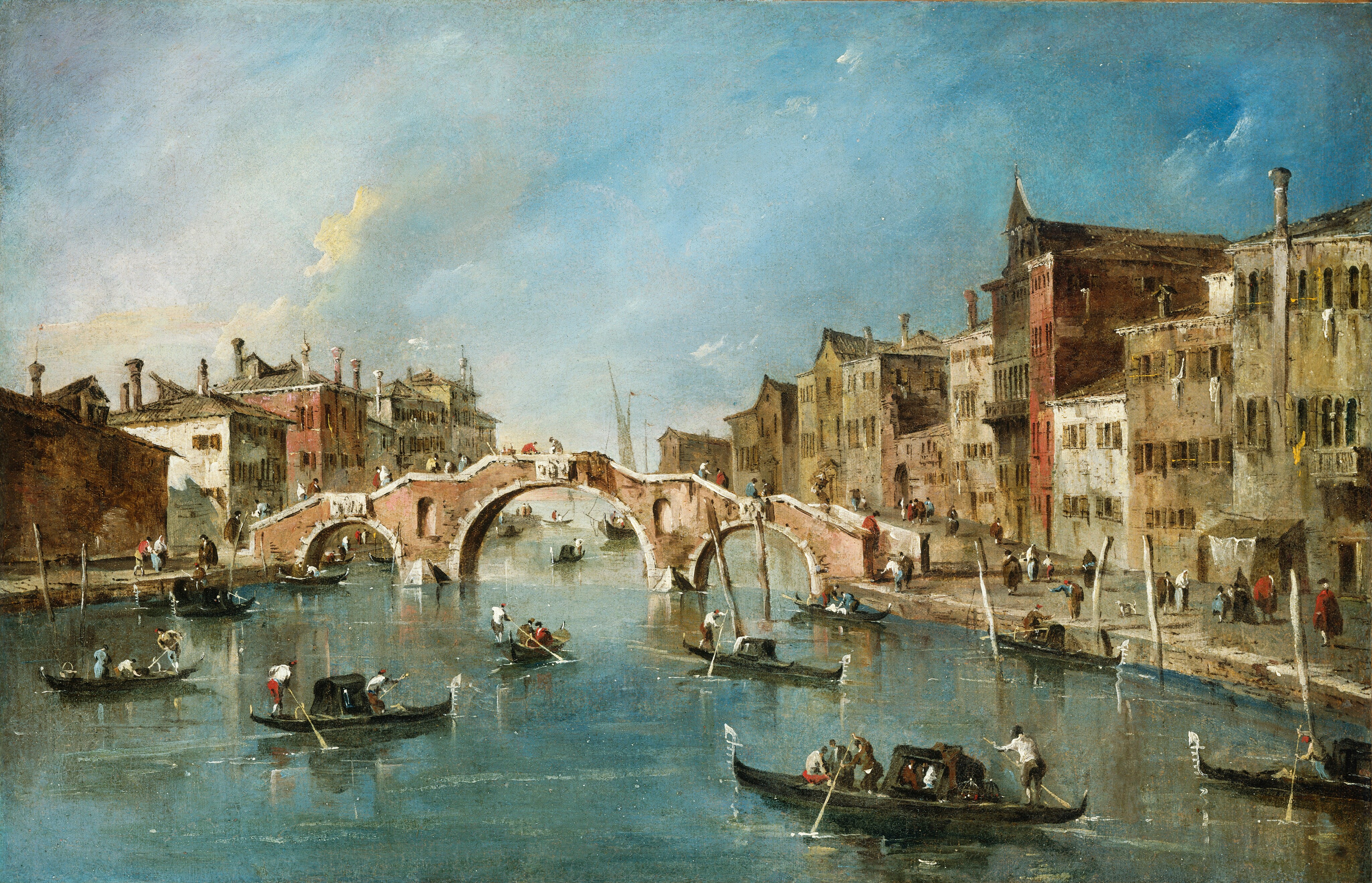 From a point of view over the water, we look across a bustling canal at a bridge, which is flanked by rows of buildings to each side in this horizontal painting. At the center of the composition, the pink stone bridge spanning the canal is edged with white stone along its three arches and the top of its stepped deck. At least fifteen people standing or walking along the bridge are painted with touches of dark red, brown, pale yellow, ice blue, white, and black. The canal is busy with gondolas and other small boats, each rowed by standing people with oars. Some boats have covered compartments while others are open with seated passengers. On either side of the canal, tightly packed buildings rise two to five stories high. The architecture includes arched windows, small balconies, and laundry hanging from lines. The colors of the buildings range from pale tan and ochre to darker reds and browns. The street-level areas are active with people walking, talking, or boarding boats. The horizon comes just under halfway up the composition. The sky above is blue with soft, streaked clouds, and sunlight illuminates parts of the scene, casting shadows along the buildings and water.