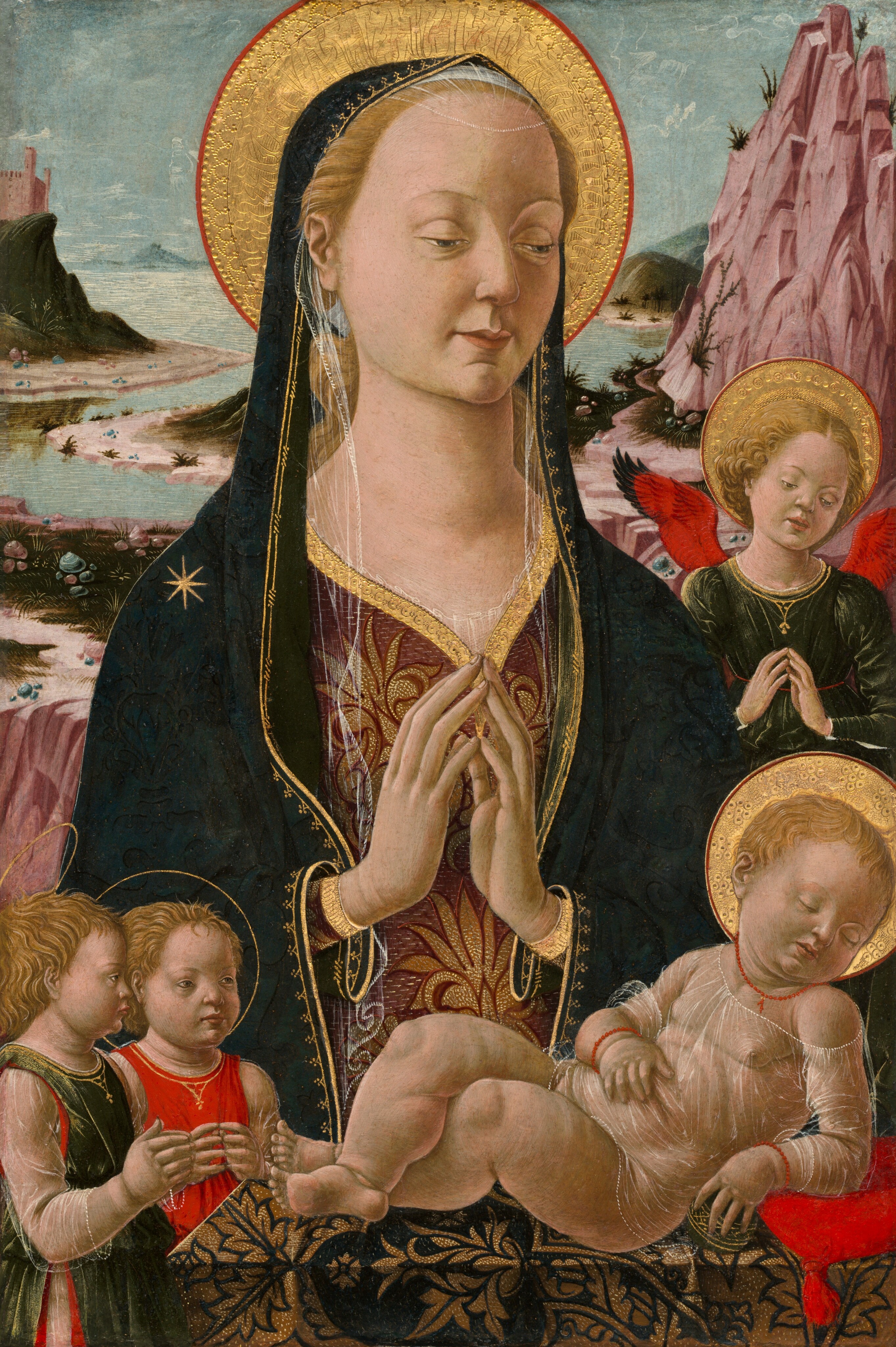 This painting depicts a woman with her hands clasped in prayer, a slight smile on her pale face. She has thin eyebrows, deep-set eyes, and a sloping nose. She wears a dark green shawl draped over her head and shoulders with ornate gold designs around the edge and hints of sheer fabric, and there is a large gold halo behind her head. Below the shawl she wears richly decorated robes with red and gold patterns. In front of her, in the bottom right corner of the painting, is a sleeping child with a golden halo, wrapped in a sheer textile. The child is adorned with a red necklace and red bracelets on each wrist. Near the bottom left corner are two more children with thin golden halos around their heads, one dressed in green and one in red, both with their hands together in front of their chests. To the right of the woman's shoulder is another child, this one in a green dress with bright red wings and a wide golden halo. All of these children have pale skin and blond hair like the woman. In the background, there is a river surrounded by pink mountains, green hills, and a castle-like structure on the left, all under a cloudy blue-gray sky.