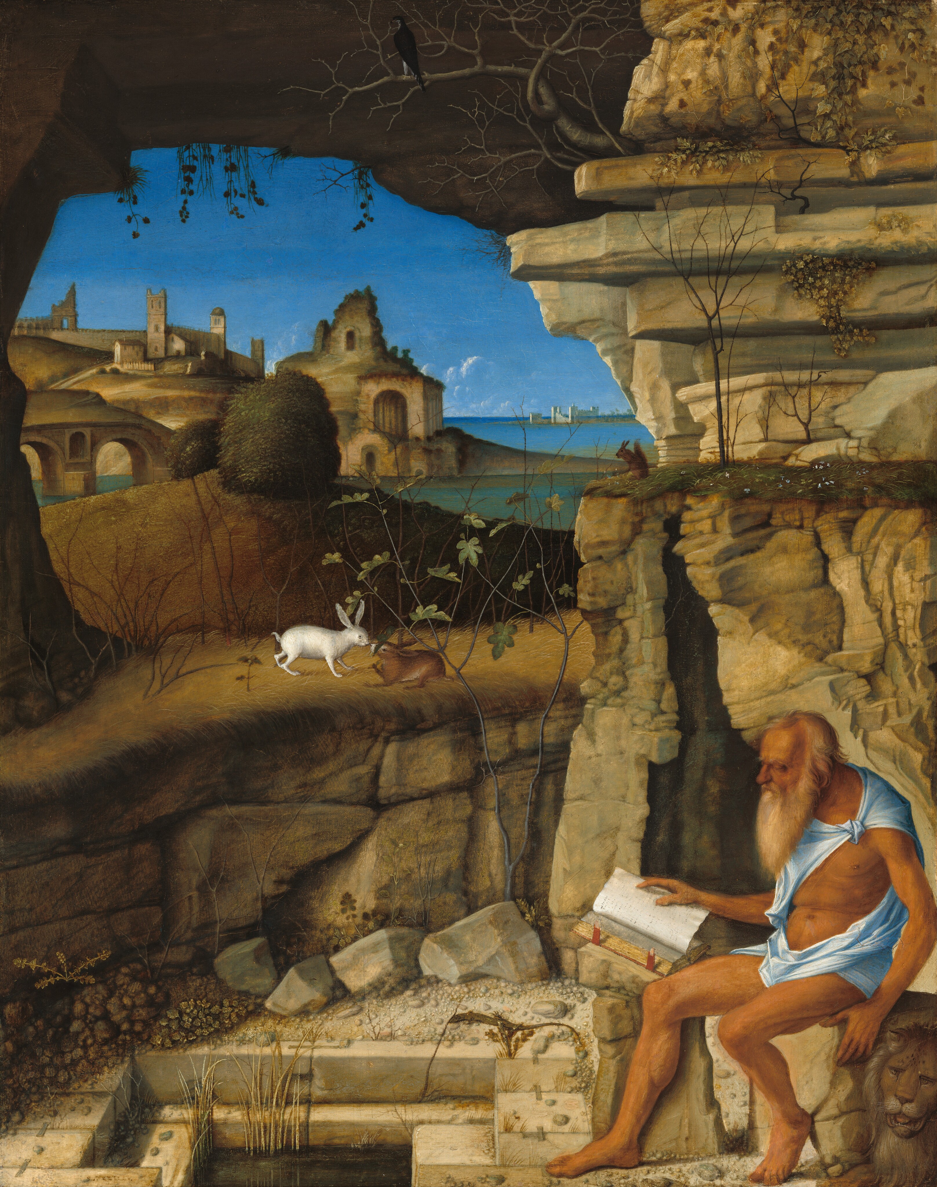 A bearded and balding man with deeply tanned skin, dressed only in a strip of robin’s egg-blue fabric around his shoulders and hips, sits reading a book on a rock at the entrance to a craggy cave, in front of a landscape in this vertical painting. In the lower right corner of the composition, the man, Saint Jerome, faces our left in profile, his head bowed toward the open book propped on the rock near the knee farther from us. His hair and beard are parchment white, and he has a prominent brow ridge, a long, hooked nose, and sunken cheeks. His arms and legs are sinewy and his torso is muscled. The blue cloth is knotted over his left shoulder and wraps around his hips. A lion lies next to Saint Jerome in lower right corner, his face toward us with his mouth open. There is a rectangular pool lined with blocky, cream-white stones at Saint Jerome’s feet, to our left. The cave behind him, to our right, has a jagged, narrow, vertical entrance, and there are rocky outcroppings above and to our left, over the pool. A stone arch spans the top edge of the painting, enclosing the scene below. Other animals appear around Saint Jerome, including a lizard near the pool; a squirrel on the grassy top of the cave entrance; and a black bird in the barren branches of a tree growing from the rocks above the cave. On the far side of the pool, two rabbits, white and brown, touch noses on a grass-topped, low, rocky wall. There is a hill with two dark green bushes beyond that. In the distance, a cluster of tan-colored, stone buildings, some in ruins, spread down a hillside to the water’s edge. Across the water to our right, deep in the distance, white buildings line the horizon, which comes about two-thirds of the way up this painting. A few puffs of white clouds float along the waterline against a vivd, azure-blue sky above.