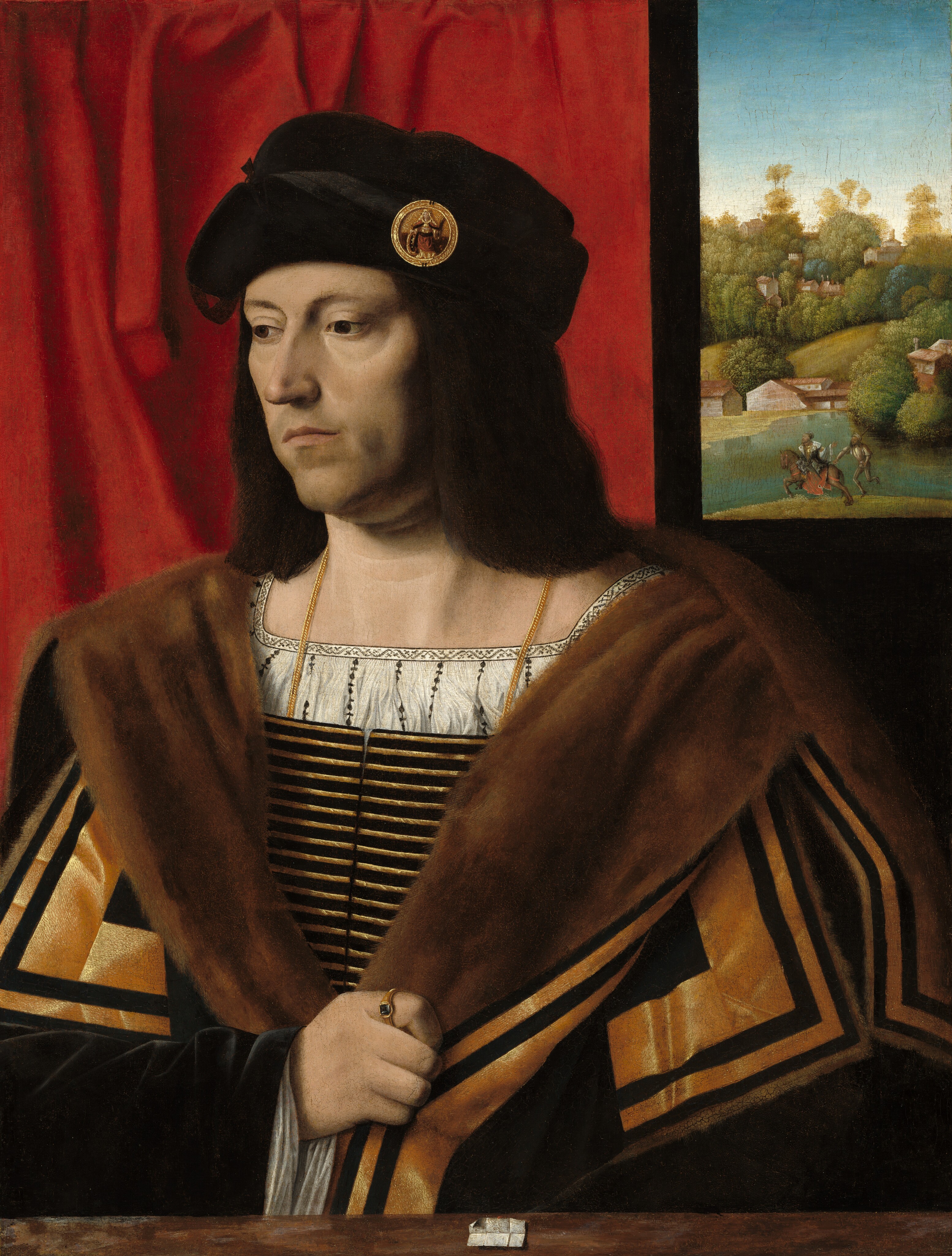Shown from the chest up, a pale-skinned, clean-shaven man wears furs and fine fabrics in this vertical portrait painting. He is angled to our left and looks down in that direction with brown eyes under slender brows. His shoulder-length, dark brown hair is topped by a soft black cap adorned with a gold medallion-like badge over the temple closer to us. The man has a long, pointed nose, his pale pink lips are closed, and his jawline is darkened by a five-o-clock shadow. He wears a white shirt with a wide, square neckline under a vest or low-cut doublet striped with black and gold. A voluminous black overcoat is lined with tawny-brown fur and edged with gold, L-shaped bands over the shoulders. He holds the sides of the coat together low on his chest with his right hand, to our left. The sleeve looks like black velvet over a translucent white cuff, and the man wears a gold ring with a gray gem on that index finger. A brown band across the bottom of the picture could be a narrow ledge in front of the man or a board or slab oriented vertically, like a frame. A small piece of white, creased paper appears to be affixed to the front of the board with red wax, a glimpse of which is shown along the top edge. A scarlet-red curtain hangs behind the man across the left two-thirds of the composition. A rectangle on the dark wall to our right could be a window opening or a painting. There we find a hilly landscape with trees, buildings, and water. Close to us in that distant view, a man wearing robes and on horseback rides away from a man carrying a lance and running after the horse.