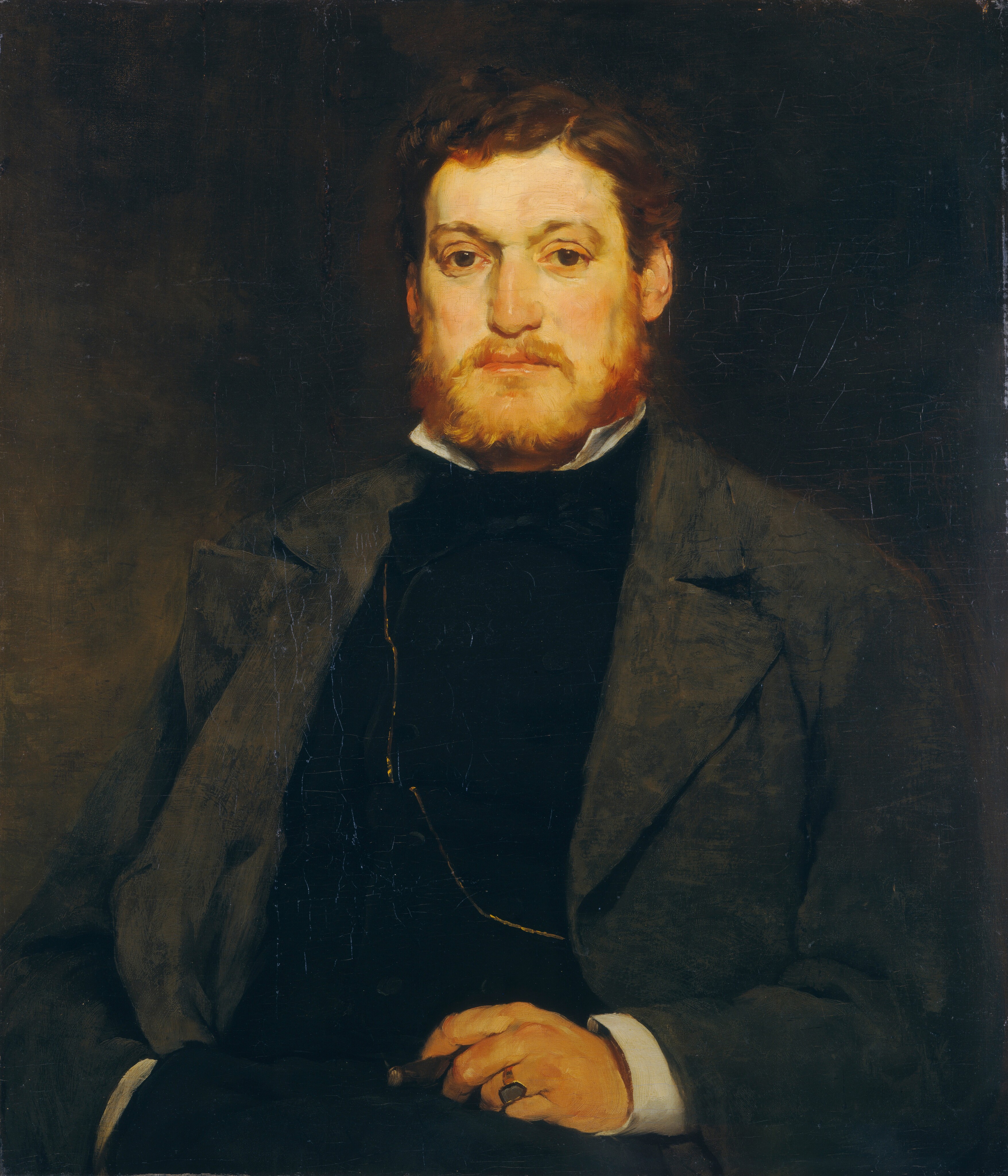 This painting shows a seated man from the waist up who looks directly at us. The man has light skin and a beard and mustache in a reddish-brown shade. His hair is similarly colored. He has a straight nose and round, dark eyes under curved eyebrows. He wears a dark suit with a white collar visible at the neck, covered by a charcoal gray overcoat. In his right hand, resting on his lap, he holds a cigar, and a gold ring is visible on his hand, with a chain across his torso. The background is dark brown and almost black in some areas.