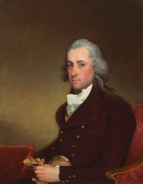 This painting is a portrait of a man. He is seated on a red cushioned chair, turned slightly to the left, facing us. He has a pale complexion and a neutral expression, with dark eyebrows, rosy cheeks, and thin lips. His hair is gray, with curls falling to the sides around his ears. He is dressed in formal attire, wearing a dark red, double-breasted coat with large golden button and a white cravat around his neck. The man holds a pair of tan gloves in his left hand, and in front of him is a piece of red furniture covered with a red cloth. The background is a muted brown gradient.