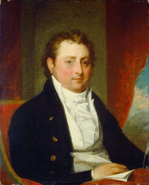 This painting is a portrait of a man from the waist up. He is seated with his body facing slightly to the right and his head turned toward us. The man has a fair complexion with rosy cheeks and a neutral expression. He has short, curly brown hair, pale eyebrows, a long, straight nose, and a weak chin. He is wearing a dark navy coat with gold buttons, a high-collared white shirt, and a white cravat. The man sits in a red cushioned chair, and in front of him is a red desk or writing surface. His right hand rests on the surface on top of a sheet of white paper, holding a white feather quill pen. In the background, there seems to be a gray column behind him, framed on either side by red curtains, and in the bottom left corner a hint of a cloudy blue sky and green foliage are visible.