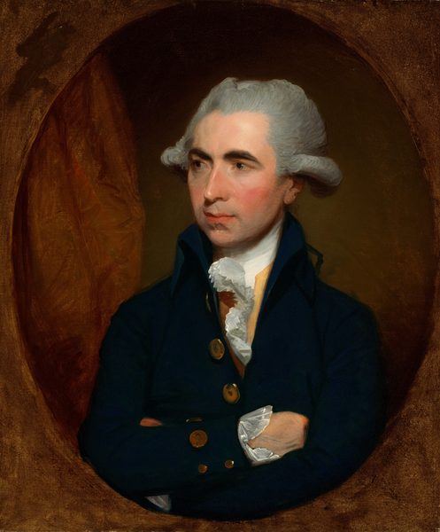 This painting is an oval portrait of a man from the waist up. His head is turned to the left, and his arms are crossed. He has pale skin and rosy cheeks, dark eyebrows, a long nose, and pink lips in a neutral expression. His gray hair is styled into curls around his ears. He is wearing a black or dark blue coat with large gold buttons over a yellow shirt with a ruffled white collar. Behind him is a warm, muted brown shade, with draped red fabric on the left. Outside of the oval portrait is a brown background.