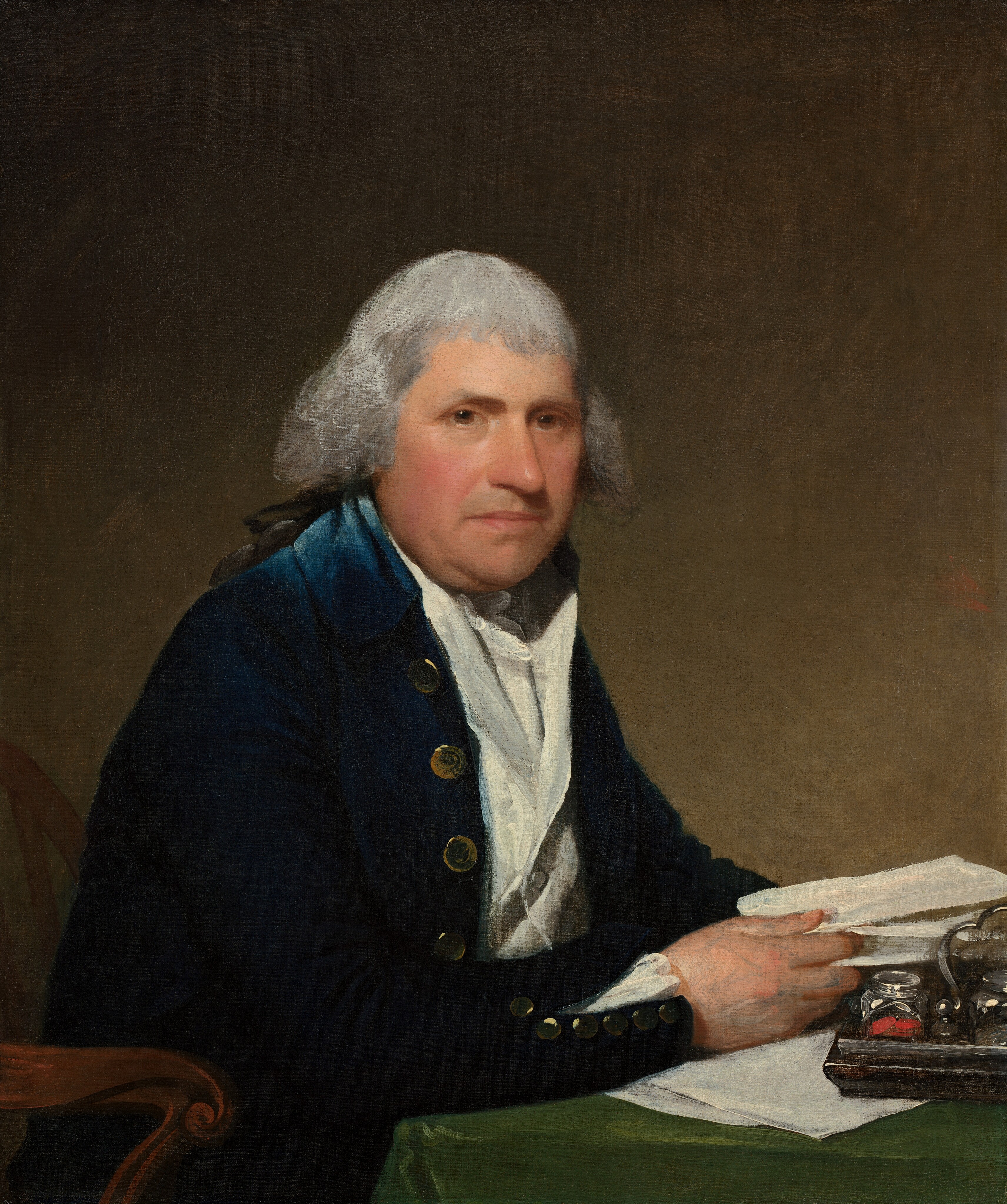 This painting depicts a seated man at a desk. His body is facing towards the right, but his face is turned towards us; he has round facial features, gray wavy hair, and a slightly flushed complexion. He is wearing a dark blue coat with gold buttons over a white shirt. His visible hand holds a paper and rests on his desk, which is covered with more papers on top of a green tablecloth. On the desk, there is also a wooden tray with silver jars. The background is a plain olive color.