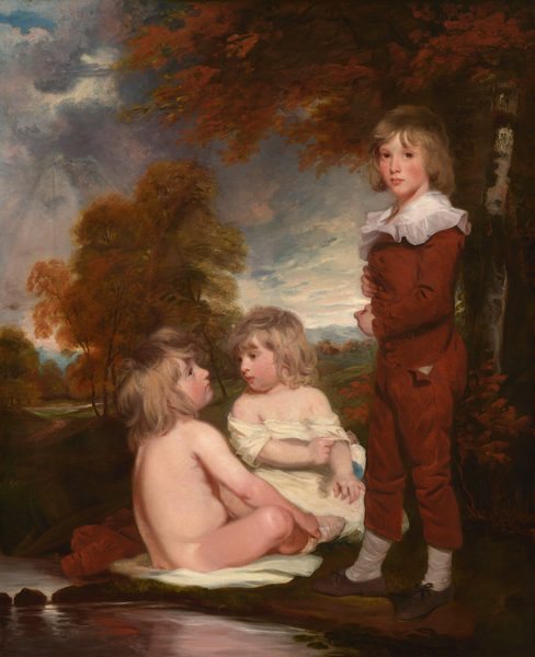 This painting shows three children in a natural setting. The child on the right is standing, visible from head to toe, while the two children on the left are seated in the grass. The standing child is positioned slightly turned to the left, with their arms folded across their chest. They have light brown, wavy hair that falls around their face, which has soft features and light complexion. This child is dressed in a russet-colored outfit with a ruffled white collar, white socks, and dark shoes. The seated child on the far left faces toward the standing child and has long, tousled, light-brown hair and a fair complexion. They are nude and sitting on a white cloth draped over the grass. The other seated child, sitting between the other two with their head turned to the left, wears a light garment partially draped over their shoulders and also has wavy, light-brown hair. The background includes trees with fall-colored foliage, a reflective stream running beside the children, and distant, cloudy skies.