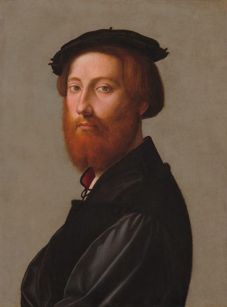 This painting is a portrait of a man depicted from the chest up, his body in profile, facing left, with his head turned toward us. He has pale, pink-toned skin, a full reddish-brown beard, short brown hair, arched eyebrows, a long nose, and thin pink lips in a neutral expression. He is wearing a black coat with a white garment and red collar peeking out by his neck. He also has a black beret or hat on his head. The background is muted gray.