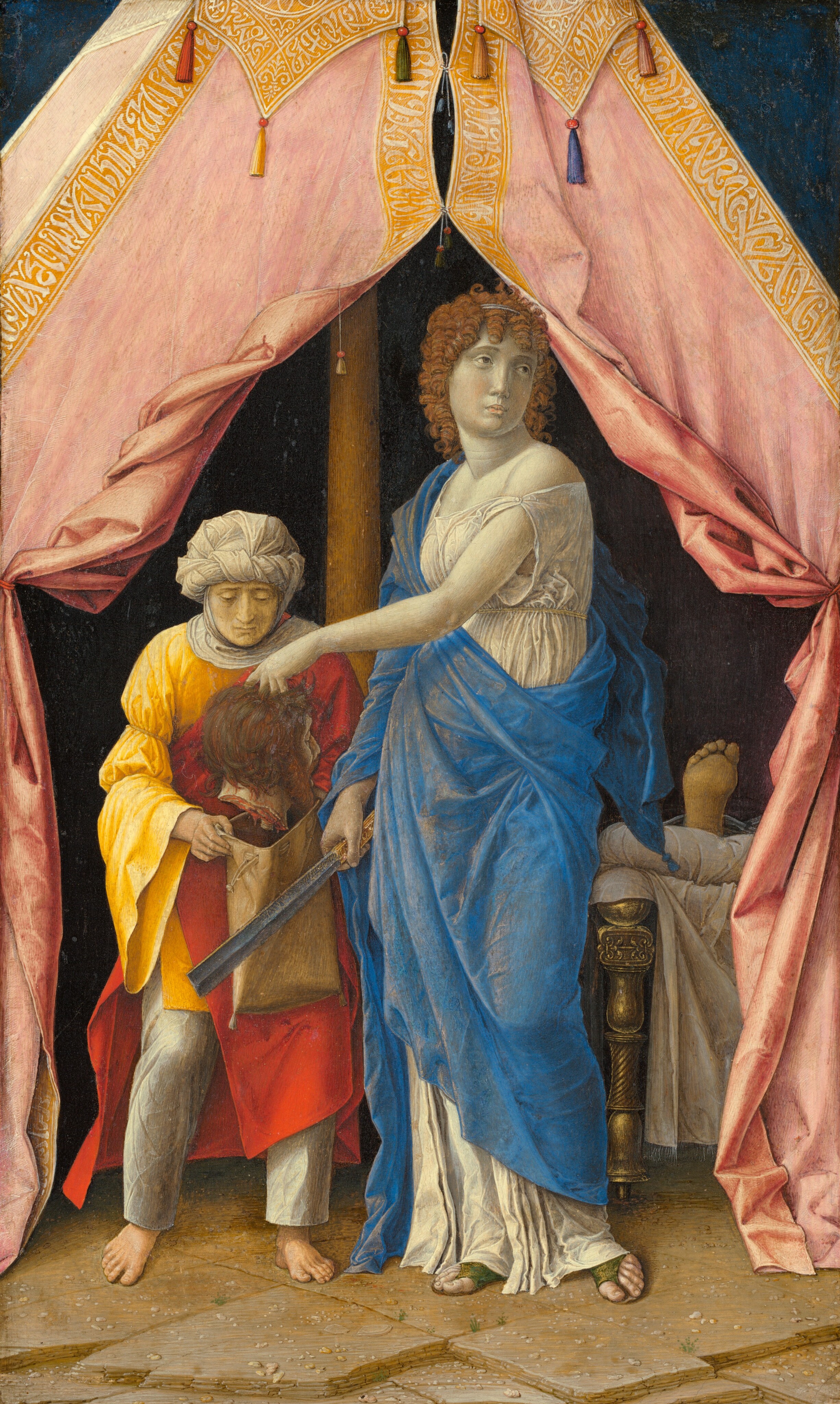 Standing at the entrance of an open tent, a woman holds the severed head of a bearded man over a sack held open by another person in this vertical painting. All the people have pale, ivory-white skin. To our right, Judith, who holds the head, stands with her body angled to our left. She looks back over her shoulder, off to our right, with light brown eyes. She has a long nose, smooth cheeks, and her small, peach-tinged lips are closed. Tightly curled, amber-brown ringlets frame her oval face and fall to her shoulders. Her loose, pearl-white dress, which is almost the color of her skin, falls off one shoulder and is belted just below her bust. A long, ultramarine-blue cloth drapes over one shoulder and arm, and around her body. Open-toed, moss-green sandals peek out from beneath her hem. Her right hand, to our left, grasps a long, straight, iron blade by her hip. The blade has a ridge up along its center, and the tip is cut straight across. She holds up the severed head in her other hand, so that arm crosses her body. The severed head faces away from us so only a sliver of the nose, cheek, and one closed eye are visible. The head has chestnut-brown hair and beard, and the mouth is open wide. To our left, the attendant holding the sack looks down at the head, her face framed by a white cloth that wraps around her head, under her chin, and across her shoulders. She wears a canary-yellow tunic over silvery-gray pants. A red cape drapes over one shoulder and around her body. She is barefoot. The tent is supported by a wooden pole, just beyond and between the pair. The gold-edged, rose-pink flaps of the tent have been pulled back and tied to each side. The interior beyond them is dark but the end of a gold bed draped with white cloth and one bare foot, the sole coming toward us, emerges from the shadows, to our right of Judith. The ground beneath the tent is made of tan, roughly square stones, scattered with pebbles. The peak of the tent rises off the top center of the composition, and the area to each side is midnight blue.
