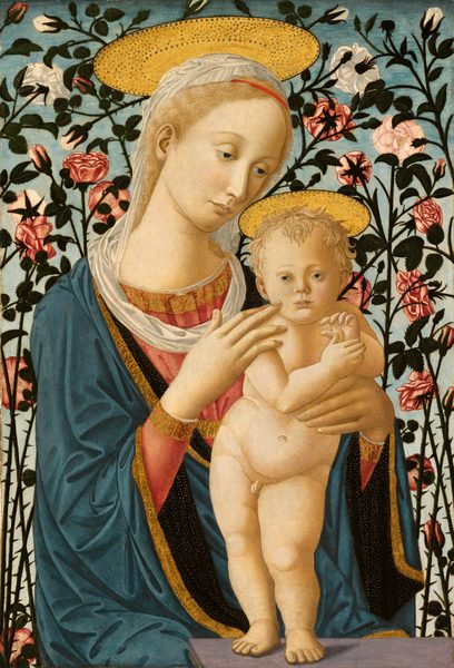 Shown from the lap up, a young woman sits behind the back corner of a gray, stone platform, supporting a small naked baby boy standing on the ledge in this vertical painting. Both have pale, almost golden skin tones and blond hair. The woman sits with her body angled to our right, and she tilts her head down toward the baby, looking past him with hooded, brown eyes. Her wavy hair is tied back and held with a thin red band above her forehead. A white veil over the crown of her head drapes down the back of her neck and wraps loosely around her shoulders. She wears a flowing, wide-sleeved robe of cobalt blue trimmed with a band of gold embroidery in designs resembling calligraphic letters. The navy-blue lining, seen at the sleeves and collar, is densely flecked with gold dots. The hems of her rose-pink dress, visible at her forearms and chest, are edged with gold embroidery and white lace. The baby stands on the ledge in front of the woman, slightly to our right. Her right hand, on our left, rests on the baby’s right shoulder with one finger brushing his cheek, while her other hand supports his other side at his waist. The child stands on pudgy legs with his left foot forward, hips sharply tilted down toward his left hip. His body faces us, but his brown eyes look over and past our left shoulder, into the distance. He has short curly hair, a round face and cheeks, and delicate facial features. His hands are raised to his chest so the thumb of his right hand touches the palm of his left. Flat, plate-like golden halos seem to rest atop both of their heads. Each halo has a black rim and is decorated with rings of dots. Filling the background immediately behind them, crisscrossing branches of a thorny rosebush fills the panel. More than two dozen white, pink, and red roses are shown in all stages, from bud to bloom, and the branches are lined with jagged-edged, deep green leaves. The roses are set against a cloudless sky that fades from powder blue along the top to nearly white along the bottom.
