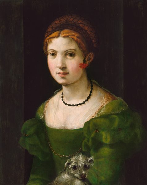 This painting depicts a woman with fair skin and orange-brown hair under a black net, wearing a green dress with puffed sleeves and sheer details around the wide neckline. Her body is slightly angled to the left, and her eyes are pointed slightly below us. She also wears a thin gold chain around her neck and a smaller black bead necklace, with a red flower behind her left ear that hangs downward. She has a straight nose, arched brown eyebrows, rosy cheeks, and pink lips in a neutral expression. A small, fluffy gray dog appears to sit in her lap, and the background is dark, with a few vertical gray lines.