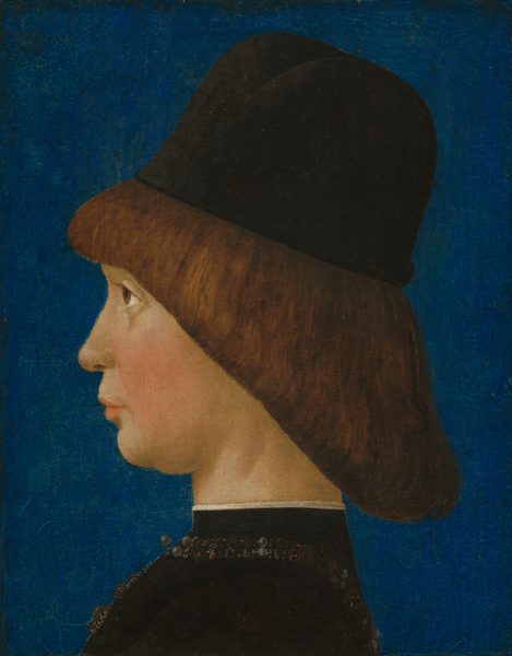 Shown from the shoulders up, a pale-skinned boy faces the left in profile against a lapis-blue background in this vertical portrait painting. He stares steadily forward with brown eyes, rosy cheeks, and closed pink lips. His chin is pulled slightly down and back. The boy's brown hair falls from bangs across his forehead in a straight, diagonal line to the nape of his neck. He wears a brimless black cap with a high, rounded crown. His high-necked, black garment has gold, black, and pearl embellishments around the neckline and down the front. The collar is edged with white along the top.
