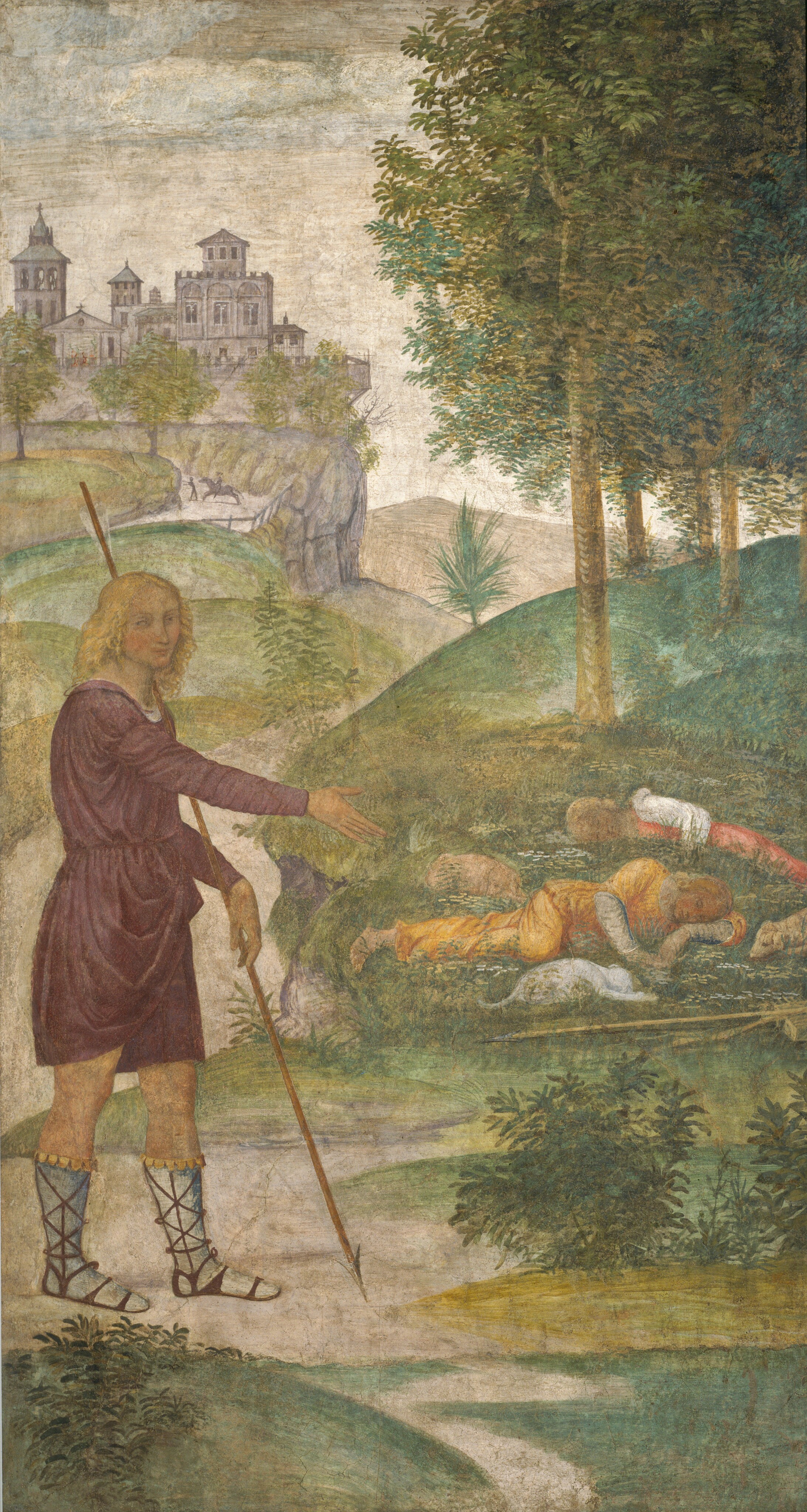 This is a painting of a pastoral scene with a person standing beside a group of sleeping people and animals. The setting includes rolling green hills and towering trees on the right, with a distant gray castle on a mountain to the left. Near the bottom left, there is a person standing and holding a long, thin staff. This person has pale skin and curly blond hair, and they wear a purple dress or robe and laced sandals. They are looking towards us, and their right hand is gesturing towards a group of two people and three animals on the right who are all curled on the grassy ground, appearing to sleep. These people wear clothes in shades of yellow, red, and white, and they also seem to have pale skin and blond hair. The animals look like small dogs. The sky above is pale gray-blue color with soft clouds.