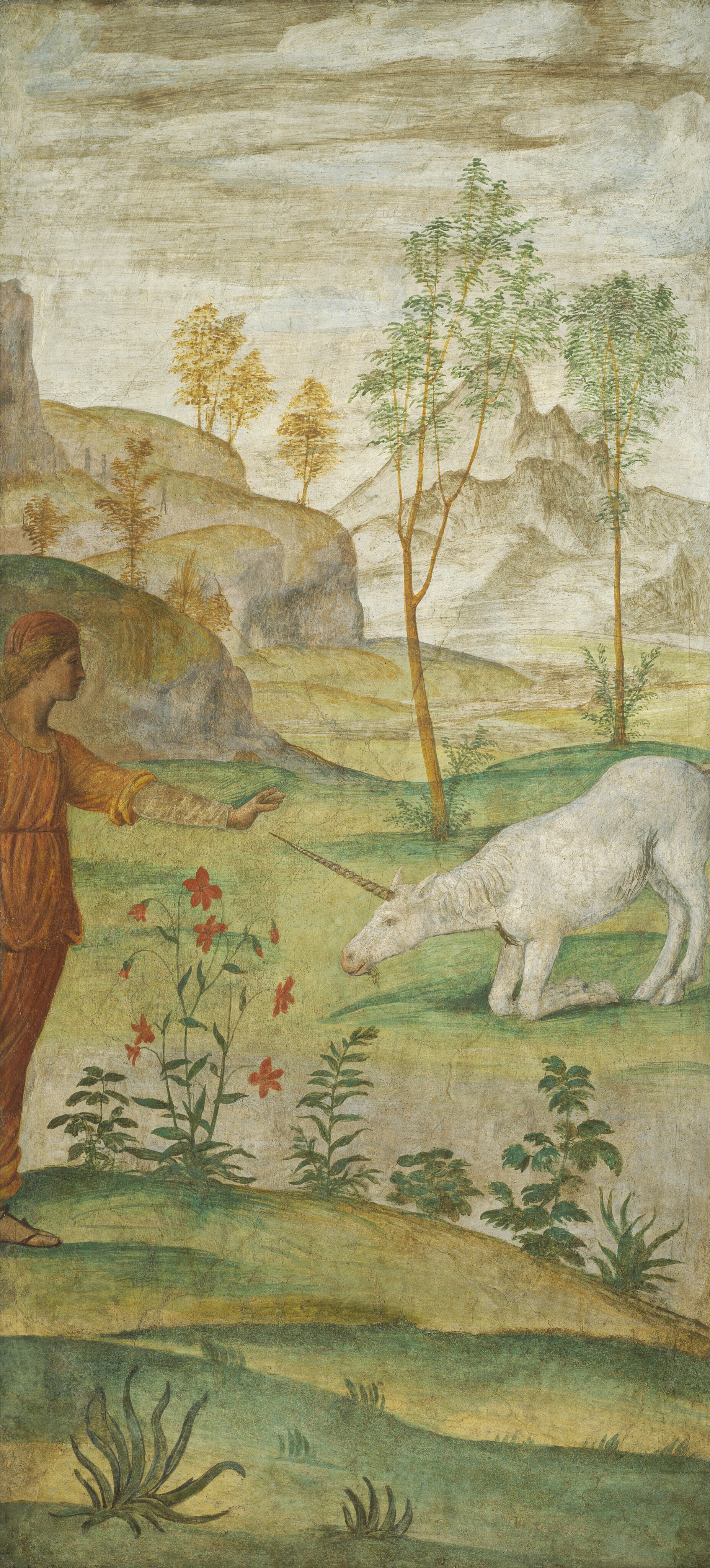 This tall, vertical fresco depicts a person in a red garment extending their arm towards a white unicorn that is bowing down on grass. The person is on the left side of the image, and only partially visible. The unicorn's long horn almost touches the person’s outstretched hand. The unicorn's back legs are extended, but its front legs are kneeling. The person and unicorn are on a light green field with red flowers and small green ferns. Behind them are thin trees in front of distant, rocky mountains. The sky above is beige, blending into the earthy tones of the landscape.