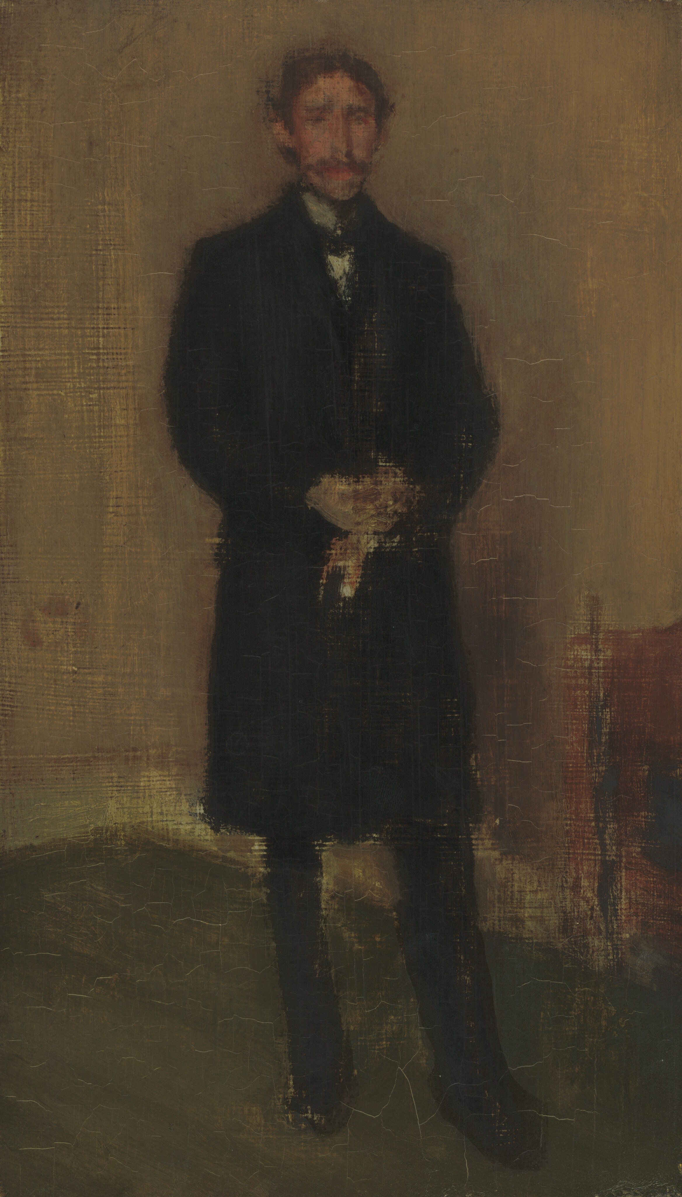 The image shows a person standing upright, facing slightly to the right. The person has indistinct facial features with a mustache and medium-length dark hair, wearing a dark overcoat and trousers with a white collar. The hands are clasped together in front. The background has a textured beige wall and dark floor, with a reddish-brown object partially visible on the right side.