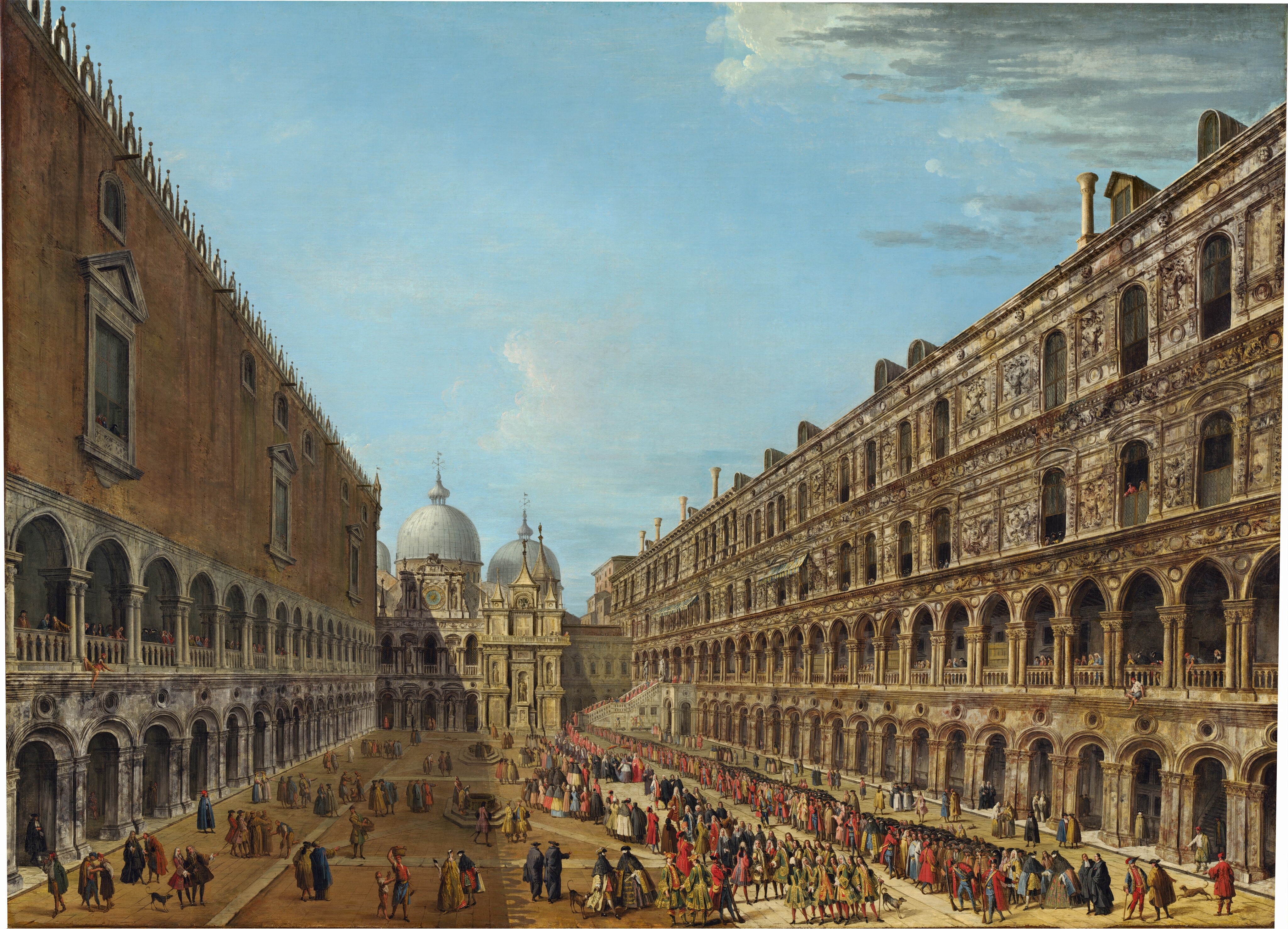 This painting depicts a square seen from above, surrounded by elegant architectural structures. On the left side, there is a large building with a red-brown facade and arched white windows with columns. On the right, there is an ornate off-white structure with arches and detailed stonework. Both of these long buildings stretch from the sides of the painting towards the center, where they converge at a gray building with tall spires and large blue domes behind it. In the square there are countless people in colorful attire, wearing shades of pink, red, blue, green, yellow, black, and blue. There are men, women, and children, and those with visible faces all appear to have light skin. Some wear white masks with bird-like noses. On the right, there is a long line of people engaging in a procession or gathering. People also line the windows of the two buildings on either side of the square. The painting is incredibly detailed, capturing architectural elements and the bustling crowd. The color palette features earthy tones for the architecture and vibrant colors for the people, all set below a pale blue sky with a few white-and-gray clouds.