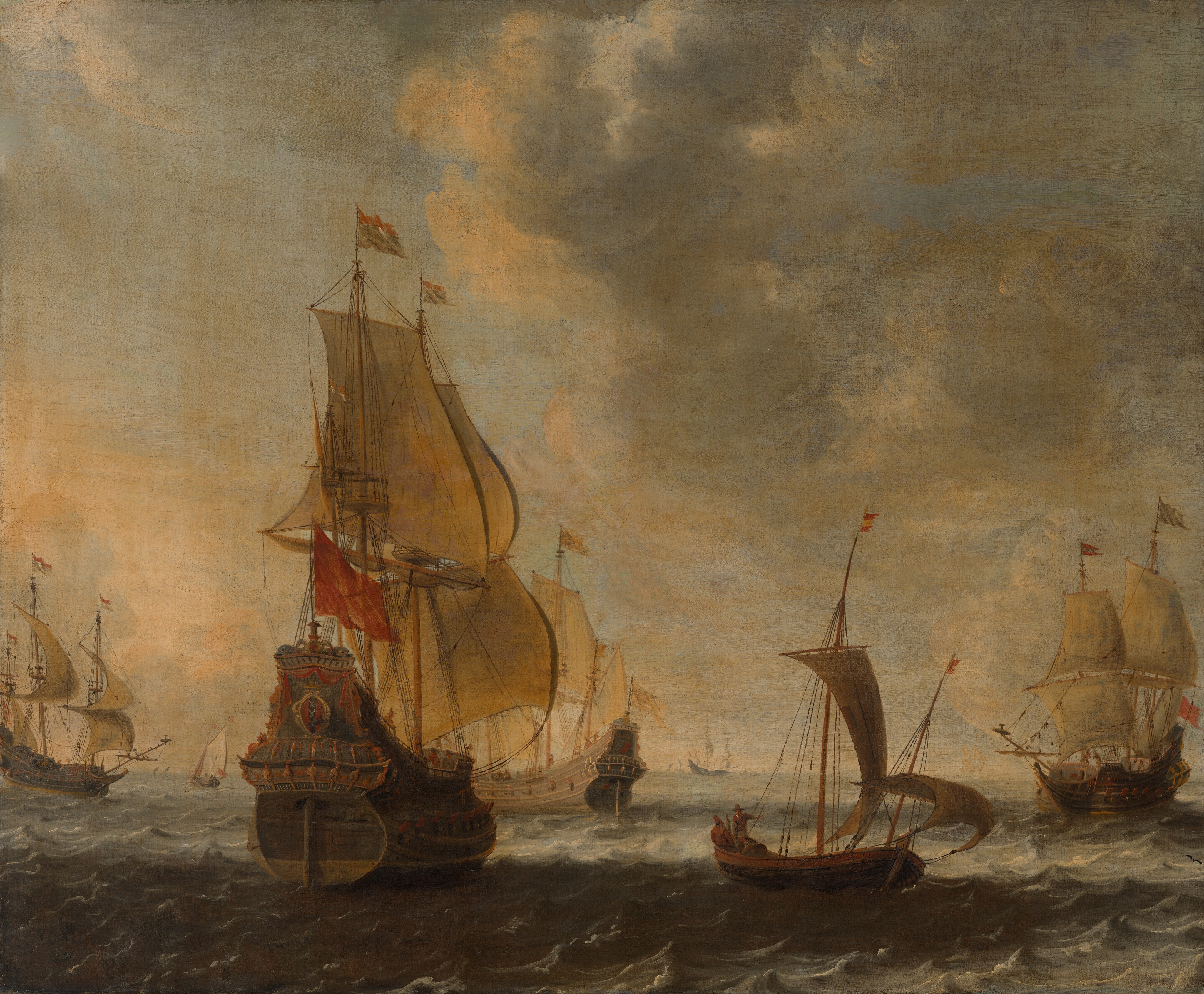 This painting shows a fleet of sailing ships on choppy water. The horizon is low, and ship sails and masts are visible far in the distance. Closest to us, five large ships are visible. Four of them are large vessels with multiple masts and sails, while one is a smaller sailboat with two sails. This smaller boat is to the right of center, and two small people are visible on it, holding ropes. To the left is the largest boat, which we see from the back. This ship is painted in a dark gray or blue color, with red accents and decorations that appear to be carved or painted on the sides. A red flag flies from this ship, as well as two smaller white and red flags. The other boats fly similar flags. On the side of this vessel, cannons emerge from small compartments. The other large vessels in the painting also have visible cannons. The water is painted in shades of gray and blue, with countless small waves. Some of the water appears to be in shadow, and is so dark it almost looks black, while other areas are a light blue-gray shade. The sky is blue, with billowing gray clouds tinged in light yellow and pink.
