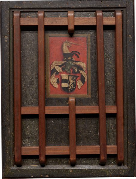 This is a painting depicting a heraldic coat of arms. The image features a detailed coat of arms with a central shield, adorned with black and gold sections, and additional decorative elements above it. There is a figure resembling a unicorn emerging from the crest. The background is a deep red hue. The artwork is displayed within a wooden frame with crossbars. This style is associated with displaying family crests and lineage.