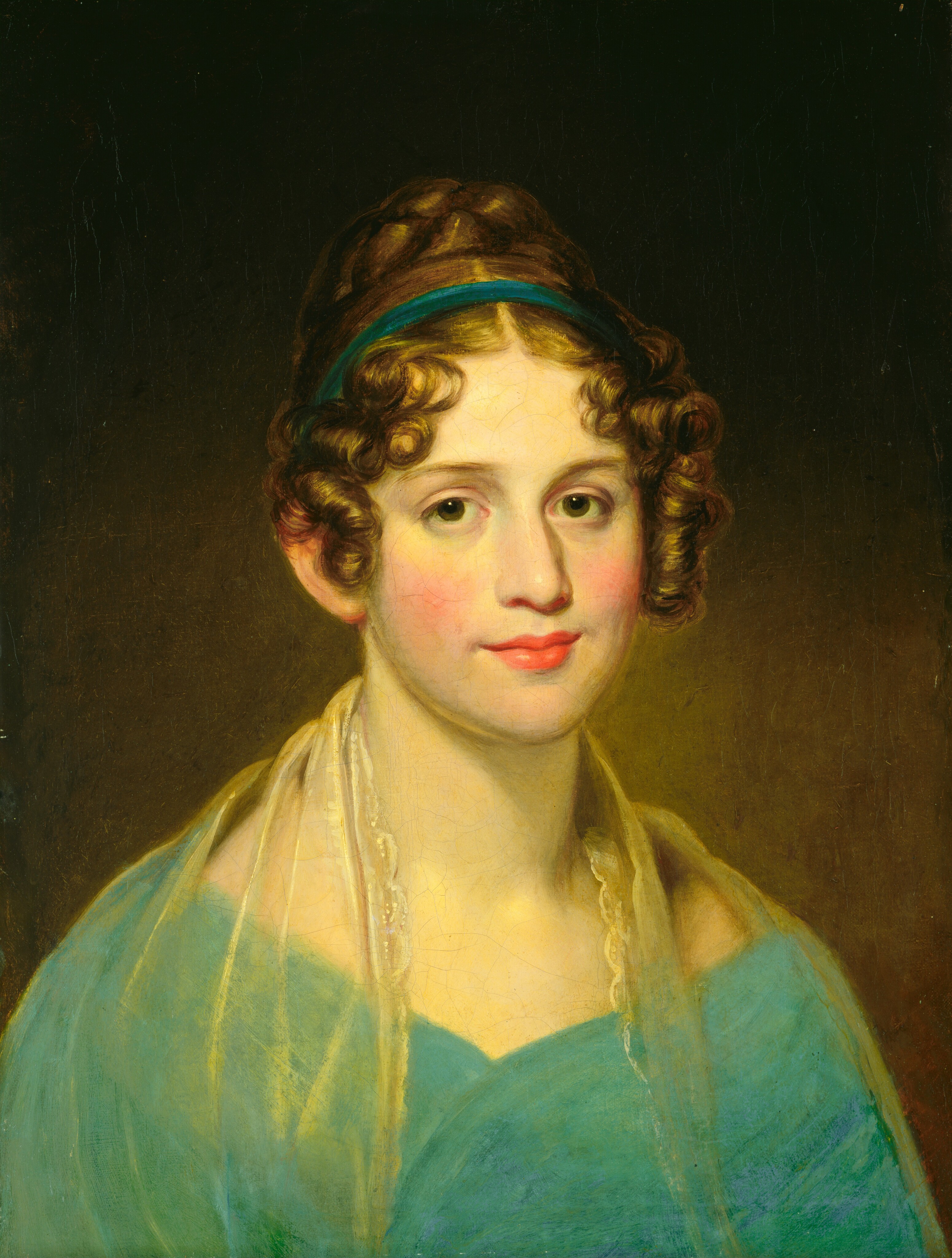 The image depicts a woman facing forward, slightly angled to her left. She has fair skin, rosy cheeks, dark eyes, red lips, and brown curly hair. She wears a teal dress with a lace scarf, and a teal headband. The background is a dark solid color.