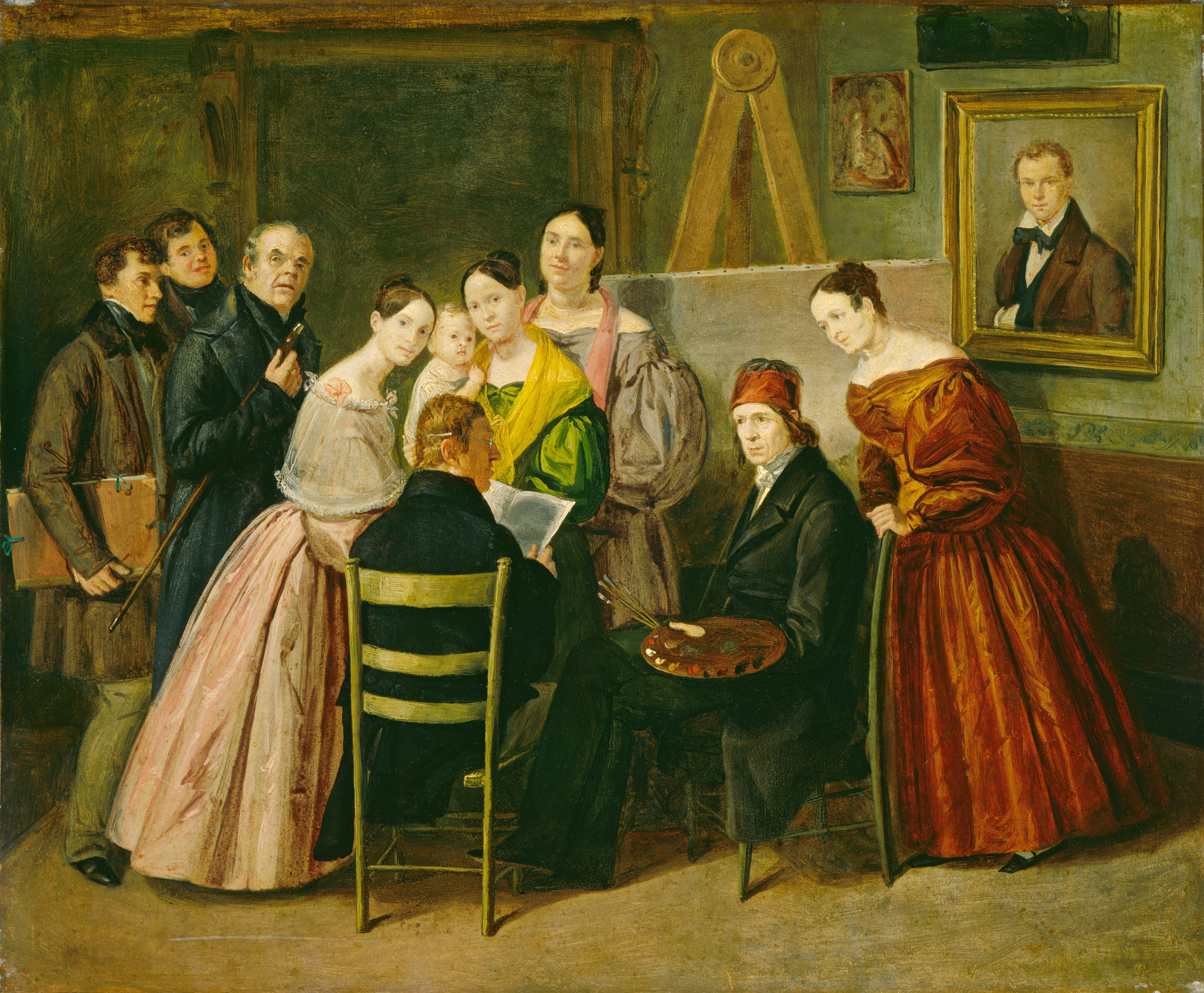 This painting depicts a group of people gathered in a room. Two men are seated, with one reading papers and the other holding a palette and paint brushes. Several standing people are gathered around these seated people, including a variety of men and women dressed in long, brightly-colored gowns or suits and jackets. Near the center a woman is holding a baby. All of the people have pale skin and most have brown hair, except for one man with gray hair. In the background, there is a large canvas or easel. On the wall on the right, there are three paintings, one of which is framed. The room's walls are decorated in muted tones of pale green, brown, and yellow. The brushstrokes of the background are thick and visible.