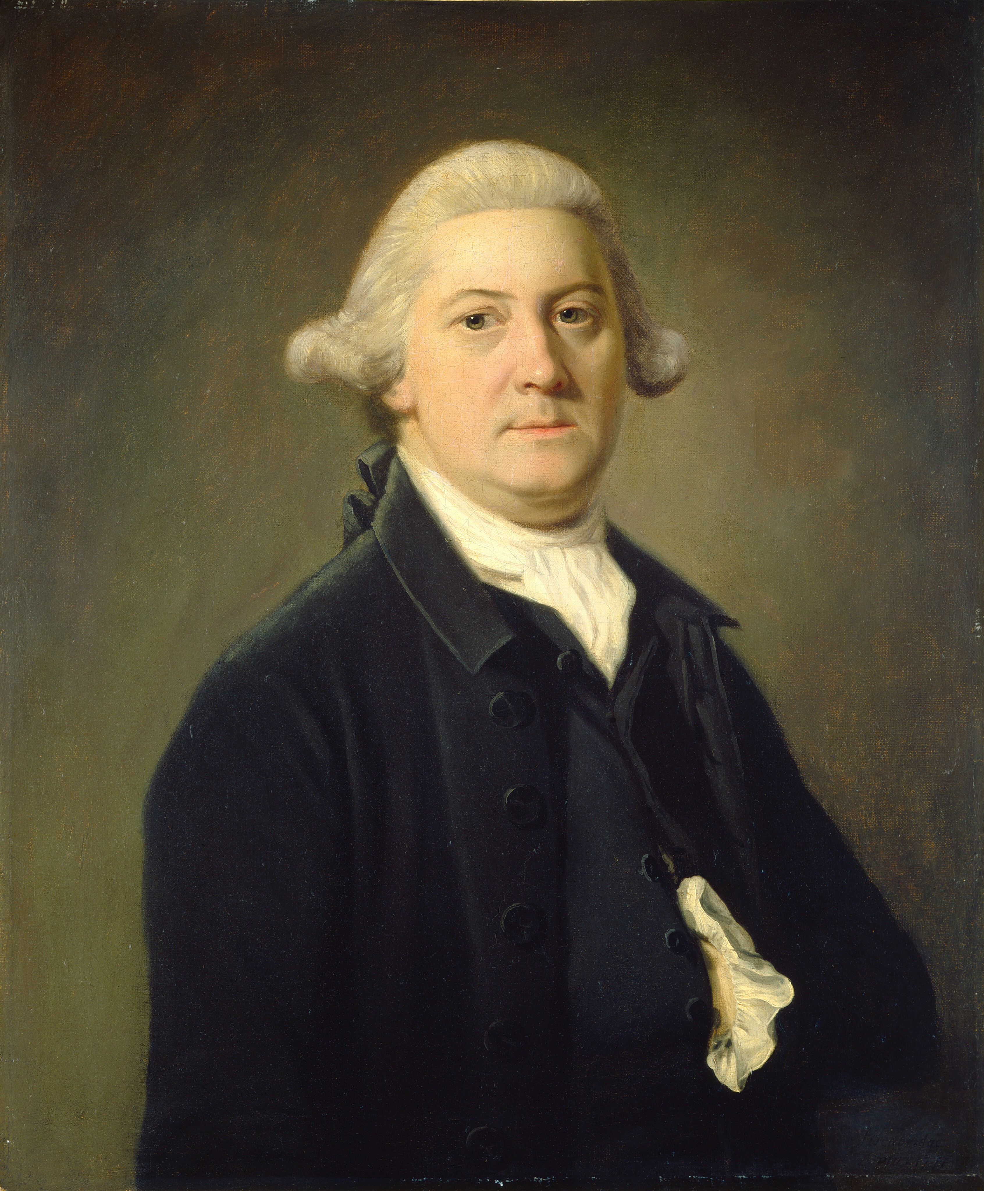 The image shows the upper half of a man's body. He is facing slightly to the left with his head turned towards the viewer, in a formal pose. The man has light-colored skin, rosy cheeks, and a calm expression. His hair is styled in a manner typical of the 18th century, with curls and tied back away from his face. He wears a dark coat with visible buttons and a white cravat around his neck. The cravat is slightly ruffled and tucked into his coat. There is no visible jewelry or objects in his hands. The background is plain, with subtle gradations of brown and dark green shades.