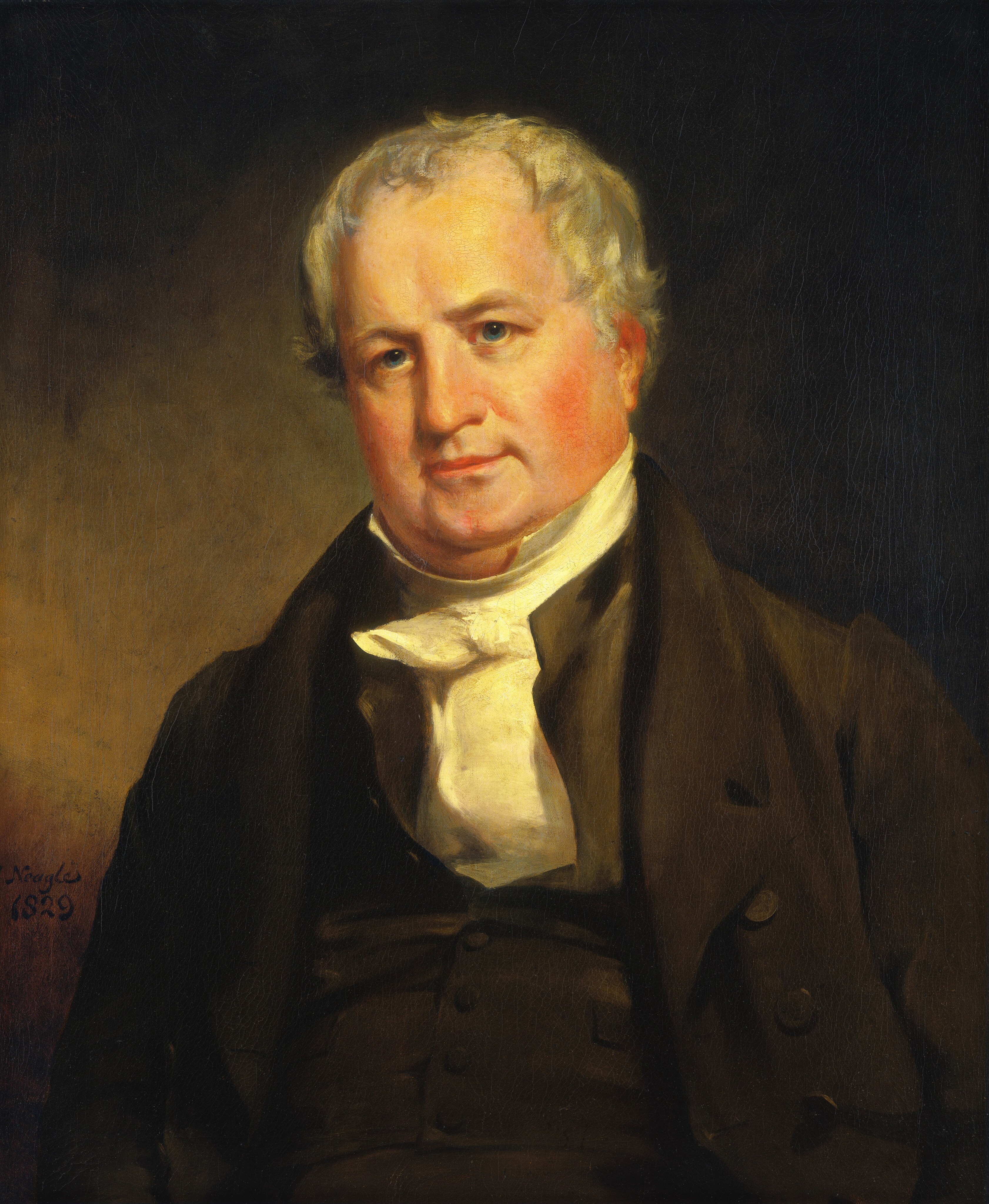 The image is a portrait painting of a man's upper body. The man is facing the viewer directly, slightly leaning back. He has a round face with prominent cheeks and fair complexion. His hair is short, curly, and gray, framing his face. He is wearing a dark coat over a waistcoat and a high white cravat tied elegantly around his neck. The background is warm, muted brown. There are no visible objects or jewelry. The painting is signed by the artist on the left side with the name "Noyes" and the year "1829".