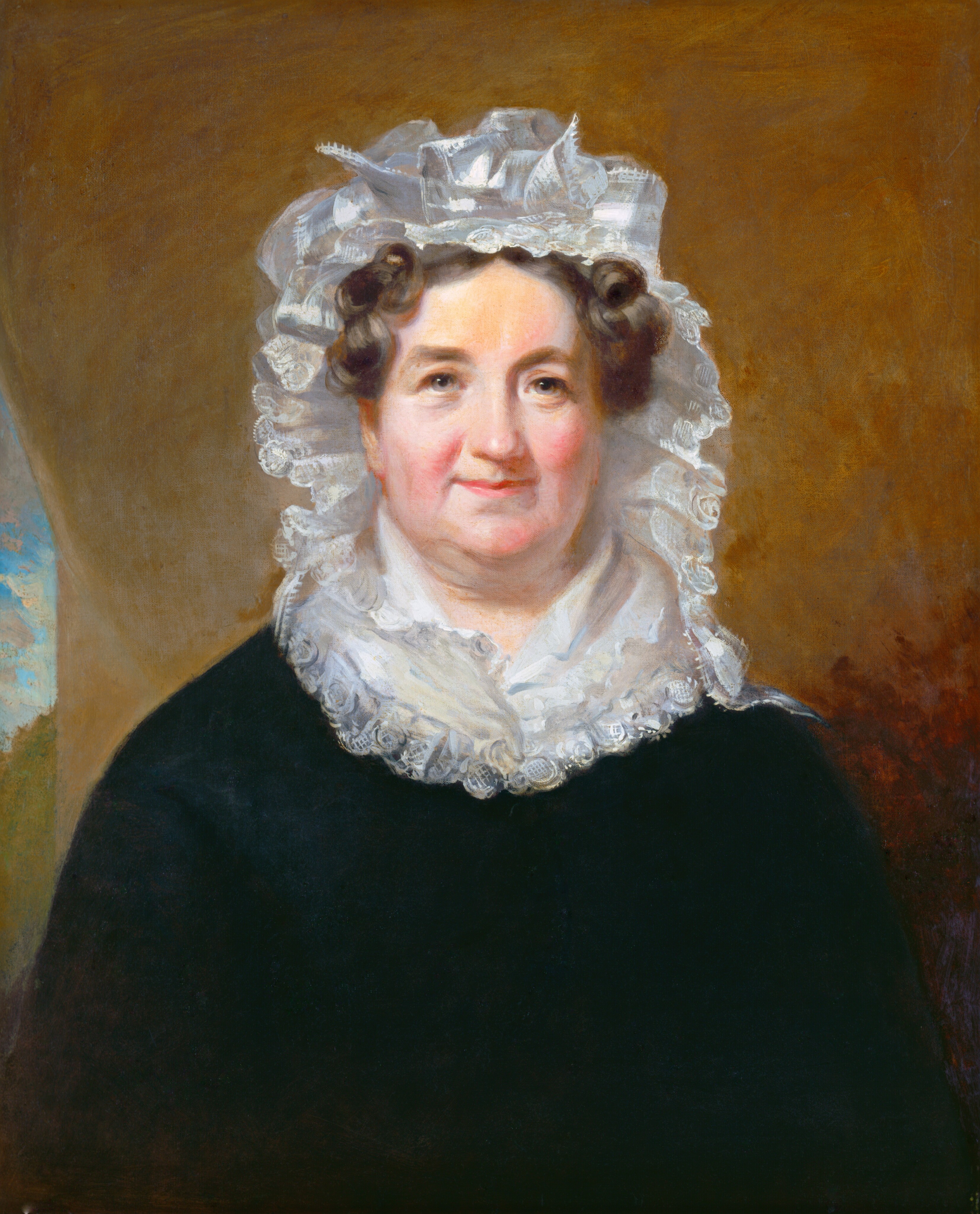 The image displays an upper-body portrait of a seated woman. She has fair skin, rosy cheeks, dark hair styled in tight curls, and is wearing a white lace bonnet with ribbons. She is dressed in a dark dress with white lace at the neckline and has a subtle smile on her face. The background is a plain, warm brown color with a lighter area on the left.