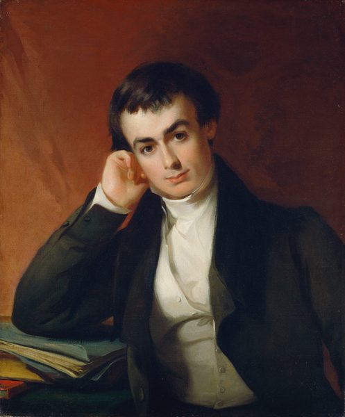 The image shows a portrait of a person from the waist up. The subject has their head resting on their right hand, propped up on their elbow. Their face is turned slightly towards the viewer, showcasing distinct facial features including dark, well-groomed hair, expressive eyebrows, and focused eyes. The person is wearing a dark jacket over a high-collared white shirt, fastened with visible buttons. In front of them is a stack of books or papers. The background is a warm, earth-toned color. No jewelry or other objects are visible.