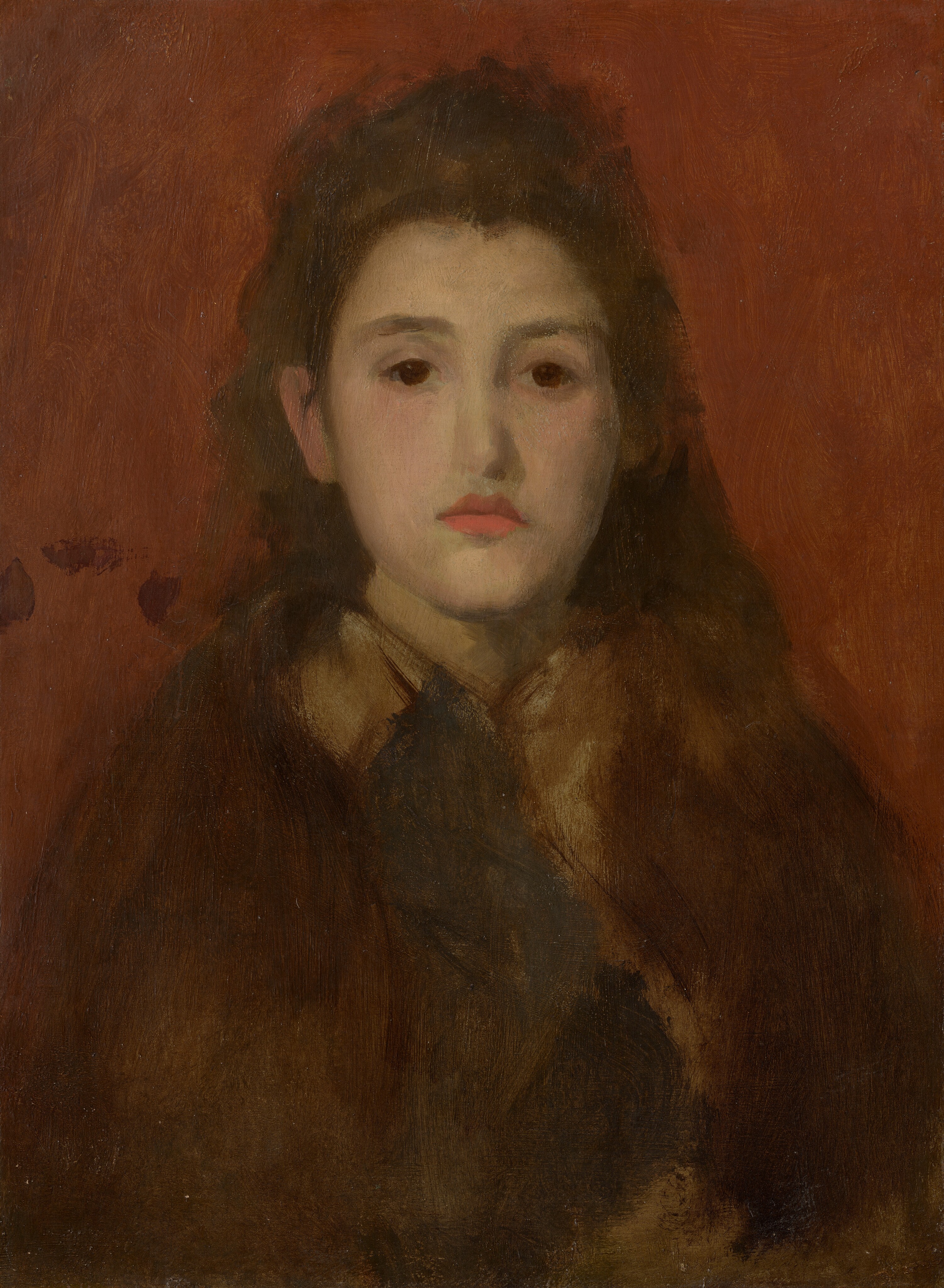 The head and shoulders of a young woman with gold-tinted, pale skin looks out over our right shoulder from against a tomato-red background in this vertical painting. The portrait is created with mostly visible, sinuous brushstrokes that make some details indistinct. With her body facing us, the woman nearly fills this composition. She looks in our direction with large, dark eyes under almost flat brows. She has an oval face, a long nose, and her full, slightly downturned coral-red lips are closed. Her chestnut-brown hair falls loosely down her back. Some locks pour over her left shoulder, to our right, and her hair is tucked behind her other ear. Her hair and clothing are especially loosely painted, so it is difficult to make out what she wears. An area of beige could be a scarf draped around her neck and down her front, or a dark, coffee-brown cloak could be open over a lighter garment beneath. The red background is painted with long, visible brushstrokes, and three dark brown spots are clustered against the background over her right shoulder, to our left.