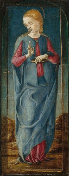 The individual is depicted from head to toe, standing upright with a slightly tilted head. The figure has delicately painted eyes, a straight nose, and lips at rest, surrounded by wavy, light golden hair that falls gently around the face and down the neck. They are dressed in flowing garments, a red robe under a blue drape that cascades down to the floor. The intricate folds of the fabric highlight the layered clothing style. In one hand, they hold a slender, closed book close to the body, while the other hand is raised with an upturned palm. Around their neck is a thin band or necklace. The background is a textured deep blue, giving a sense of depth, with some hints of earthy tones near the bottom that suggest a simple, non-specific setting.