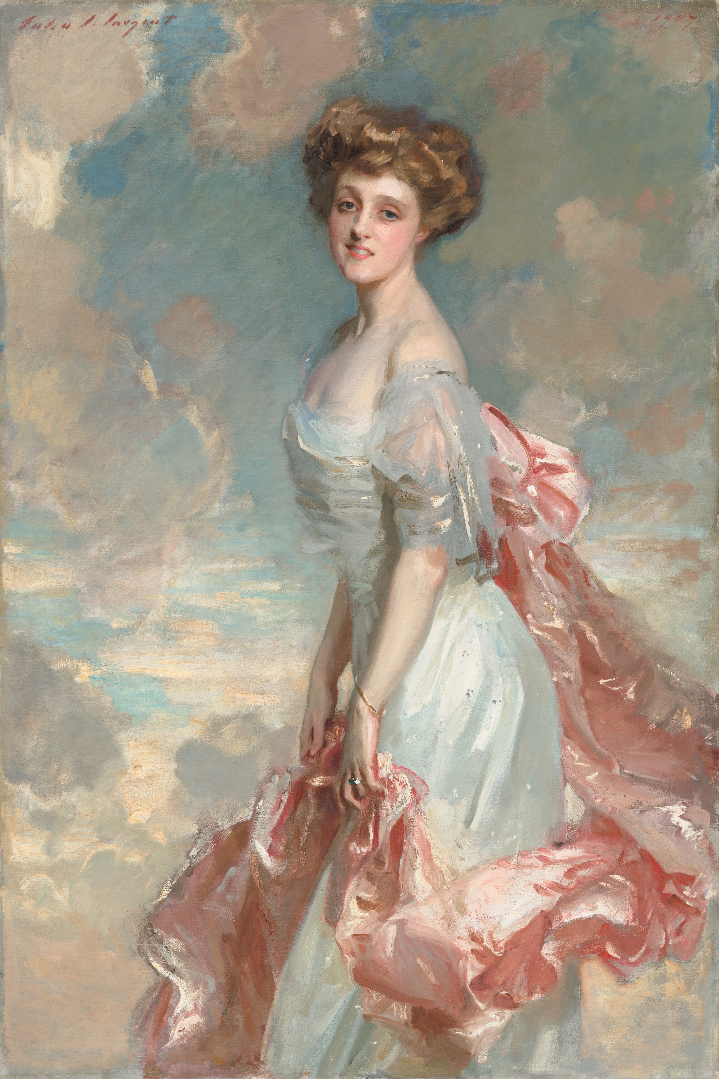 A young woman with pale, peachy skin, wearing a long, silvery blue dress with a rose-pink train looks out at us in this vertical portrait painting. She stands in front of a topaz-blue sky dotted with puffy white clouds, which are shaded with shell pink and light lilac purple. Her body faces our left in profile and she turns her smiling, oval-shaped face to us. She leans her torso slightly forward. Her light brown hair is loosely piled on her head. Her gray-blue eyes are framed by delicate brows, and she has an aquiline nose, rosy cheeks and lips, and a long, elegant neck. Light glints off the dress she wears, suggesting is silk or satin. It has a low, straight neckline and the short, fluttery sleeve we can see falls off her shoulder. A long, billowing swath of light pink fabric is attached to the back of her dress, possibly with a large bow, and it drapes in lively folds down and around the front of her skirt. She holds it lightly with both hands at her thighs. She wears a thin gold bracelet on her left wrist, closer to us, and a silver ring on the third finger of that same hand. The portrait is loosely painted, especially in the clothing, so the texture of the brushstrokes is visible in many areas. The artist signed the work with brick-red paint in the upper left, “John S. Sargent” and dated the upper right, “1907.”