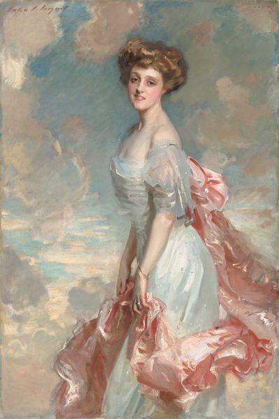 A young woman with pale, peachy skin, wearing a long, silvery blue dress with a rose-pink train looks out at us in this vertical portrait painting. She stands in front of a topaz-blue sky dotted with puffy white clouds, which are shaded with shell pink and light lilac purple. Her body faces our left in profile and she turns her smiling, oval-shaped face to us. She leans her torso slightly forward. Her light brown hair is loosely piled on her head. Her gray-blue eyes are framed by delicate brows, and she has an aquiline nose, rosy cheeks and lips, and a long, elegant neck. Light glints off the dress she wears, suggesting is silk or satin. It has a low, straight neckline and the short, fluttery sleeve we can see falls off her shoulder. A long, billowing swath of light pink fabric is attached to the back of her dress, possibly with a large bow, and it drapes in lively folds down and around the front of her skirt. She holds it lightly with both hands at her thighs. She wears a thin gold bracelet on her left wrist, closer to us, and a silver ring on the third finger of that same hand. The portrait is loosely painted, especially in the clothing, so the texture of the brushstrokes is visible in many areas. The artist signed the work with brick-red paint in the upper left, “John S. Sargent” and dated the upper right, “1907.”