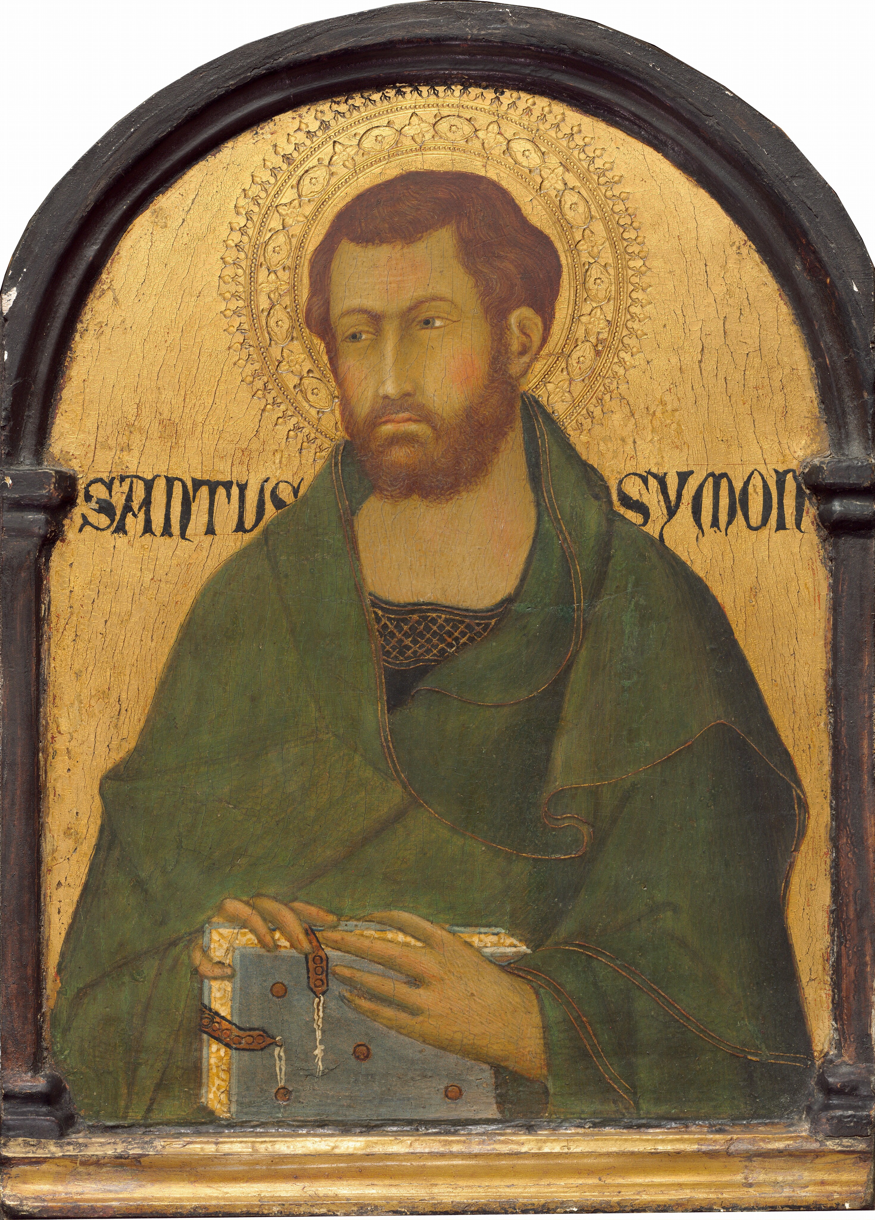 This painting shows the upper body of a man. The man has short, dark, wavy hair and a beard, and he wears a green robe over a dark garment with a neckline decorated with a gold pattern. He looks to the left, and has pale skin, rosy cheeks, arched eyebrows, and thin lips. He is holding a light blue book in his hands. Behind him, the background is golden, and there is an ornate halo surrounding his head. The words "SANTUS SYMON" are on either side of the man's head in a dark script. The painting is framed in a dark, arched border.
