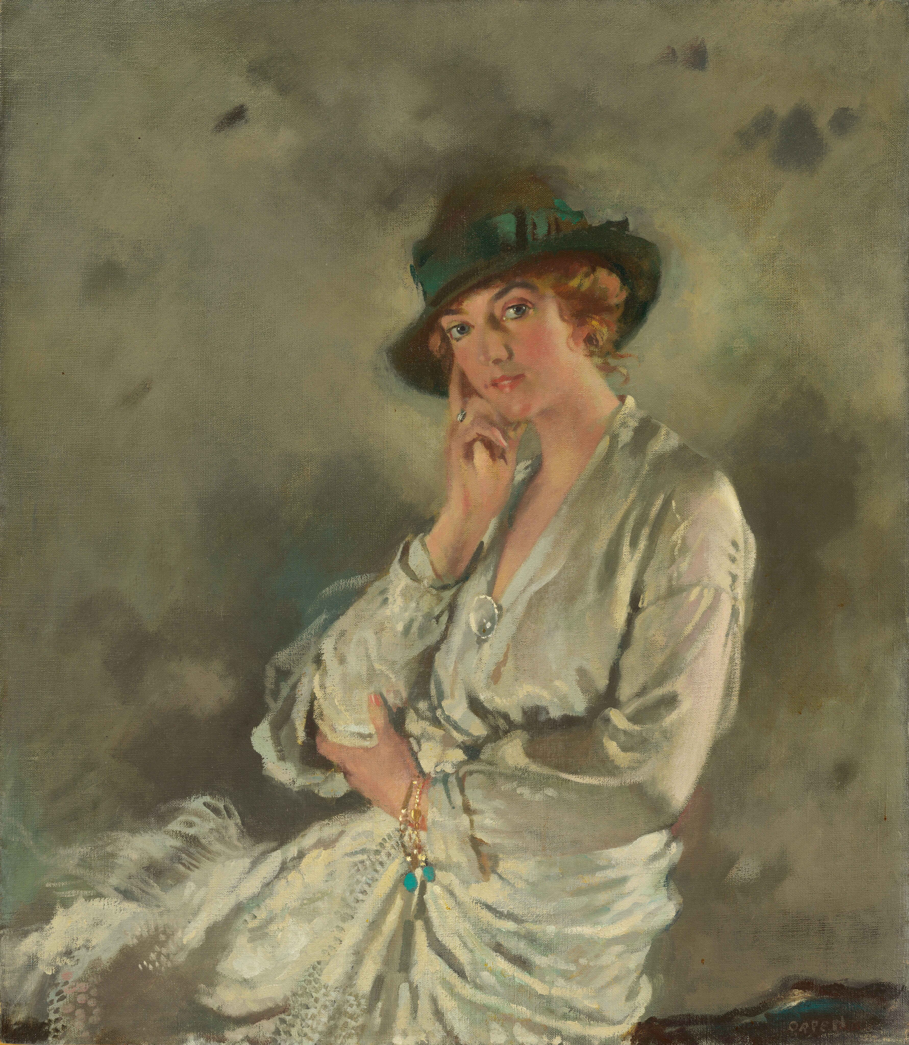 This painting shows a woman seated from the waist up. She is in a three-quarter pose facing left but looking directly at us. She has light skin, rosy cheeks, and arched eyebrows. Her reddish-brown hair is short and wavy, and she wears a dark green hat. She is dressed in a light, flowing garment with folds and a brooch on the neckline. She rests her chin on her right hand, with her left arm across her body, holding her elbow. She wears a gold bracelet with a chain and blue embellishments. The background is a gray surface that looks similar to a cloudy sky.