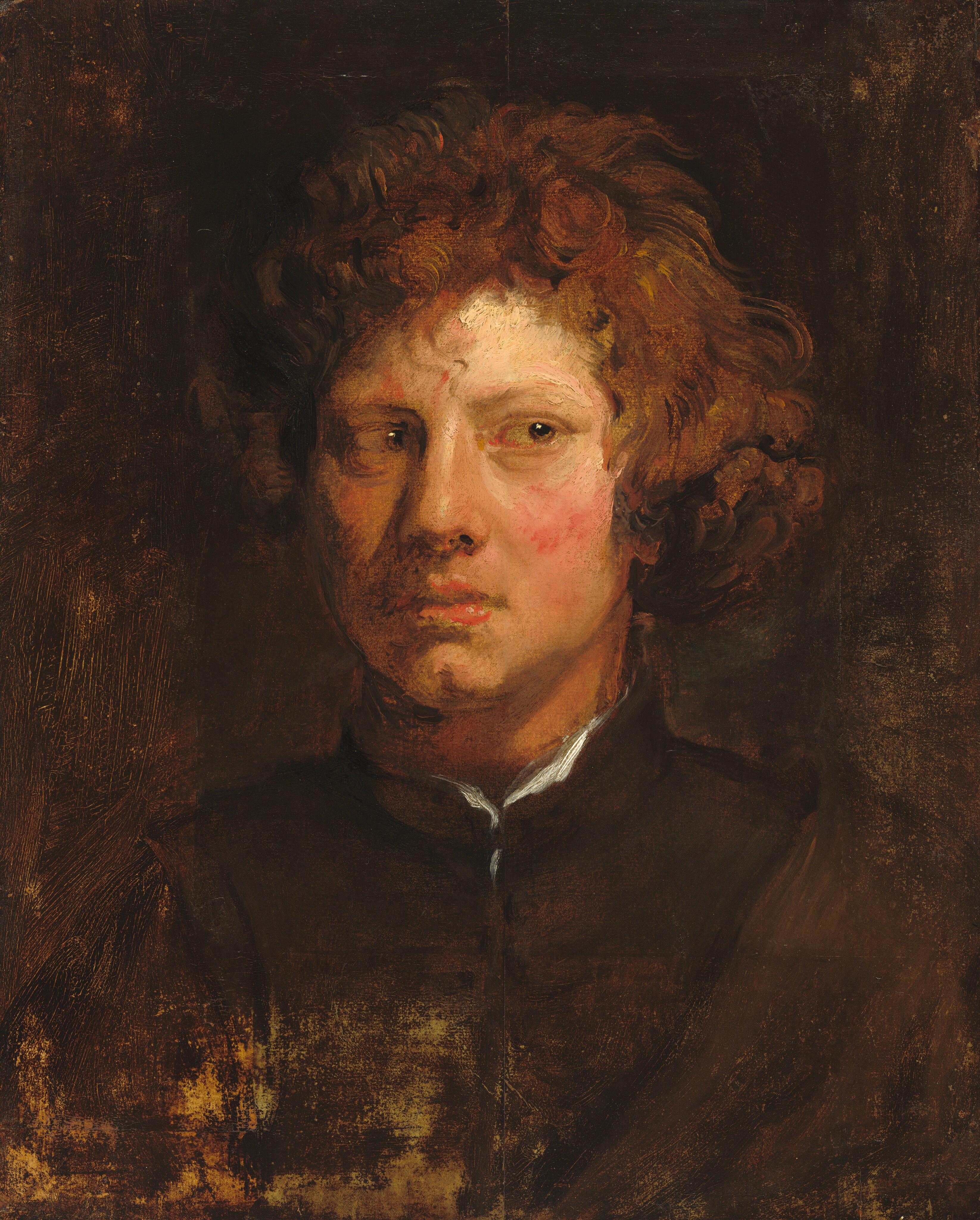 Shown from the chest up with his body and head facing us, a pale-skinned young man cuts his light-brown eyes sharply to our right in this vertical portrait painting. His slightly wild, copper-brown hair puffs around his ears and tendrils curl on his forehead. His cheeks are flushed vivid pink. His full, pink lips are closed, and he has a cleft in his rounded chin. Some darker strokes around his mouth could be a goatee. He is lit from our right, and light shines brightly on a sliver of white at the neckline of his coffee bean-brown, high-necked garment. His clothing and hair blend into the dark brown background. Brushstrokes are visible throughout, especially in the man’s face and hair. Some areas of the canvas appear thinly painted or abraded; this is especially noticeable in a lighter area at the bottom left corner.
