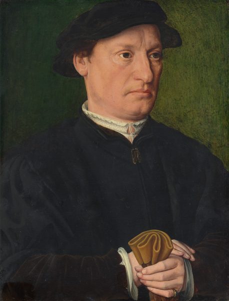 The image shows a man's upper body from the chest up. He is slightly turned to the side with his hands clasped together, holding a folded cloth. The man has a serious expression with prominent cheekbones, a furrowed brow, light facial hair, including a mustache, short brown hair mostly covered by a dark cap, and is dressed in a dark garment with a high, white ruffled collar. A ring is on his left ring finger. The background is muted green.