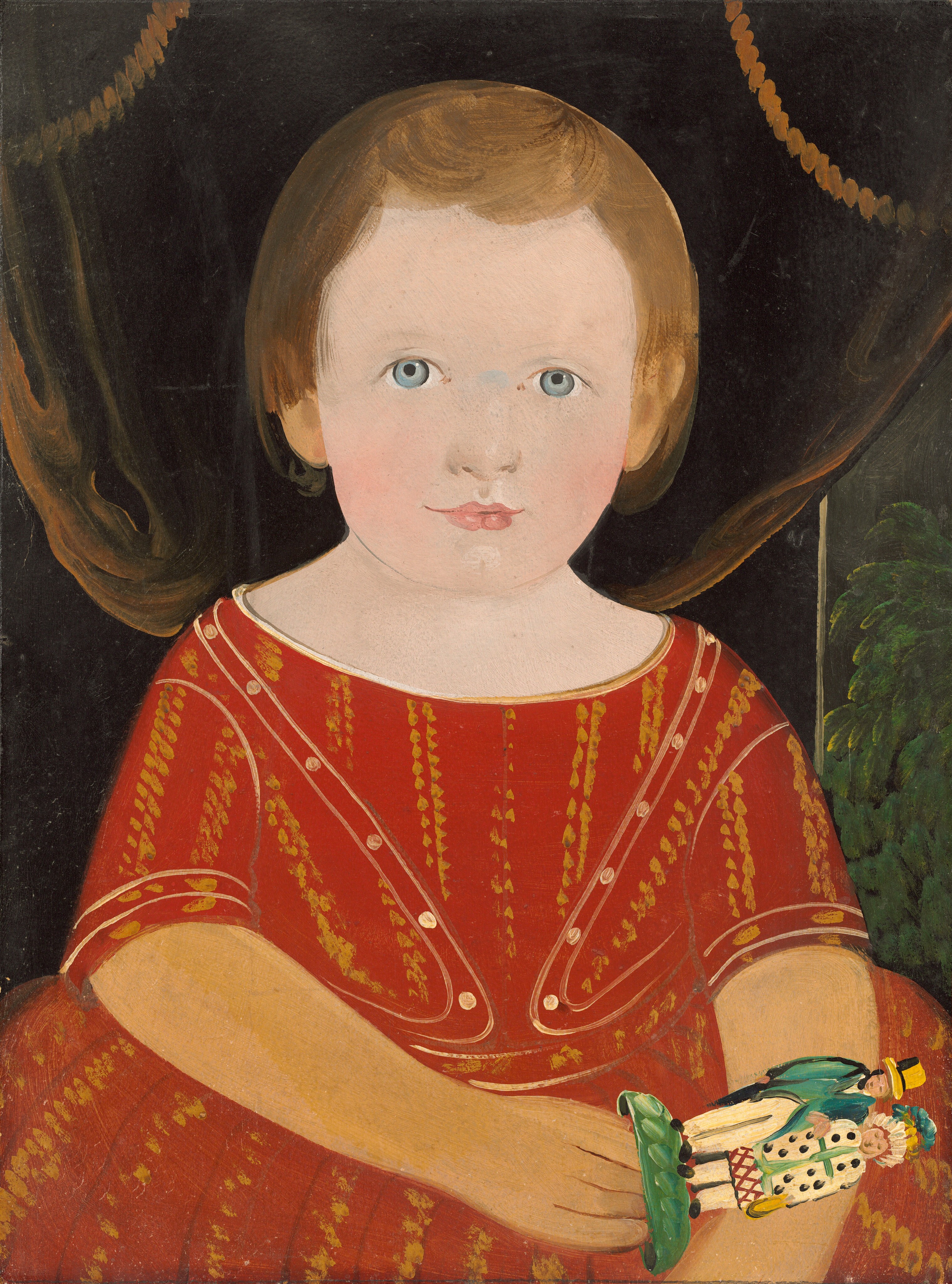 The image shows a portrait of a young child from the waist up, facing forward. The child has light skin, blue eyes, short brown hair, and wears a red outfit with gold and white patterns. They hold a small, colorful object and stand in front of dark curtains with decorative tassels, with a hint of greenery visible in the background.