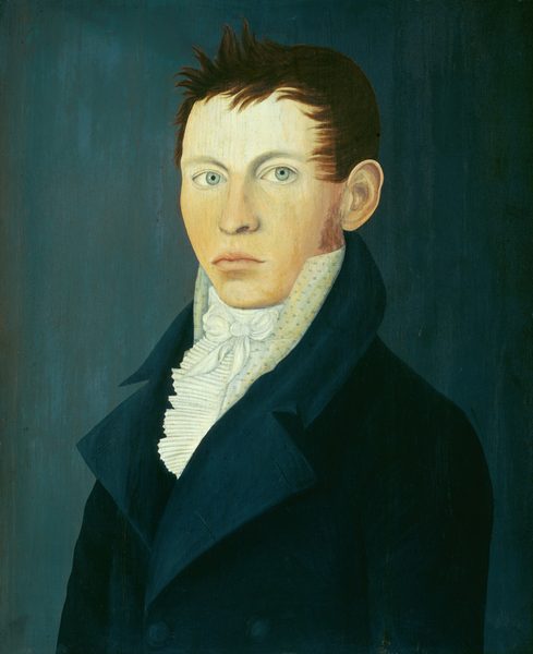 The image shows a portrait of a man's upper body. The man has a serious expression and wide eyes, with short dark hair styled in an upward manner. He is dressed in a dark coat and a high collared white shirt with a decorative front. The background is a solid dark teal color.