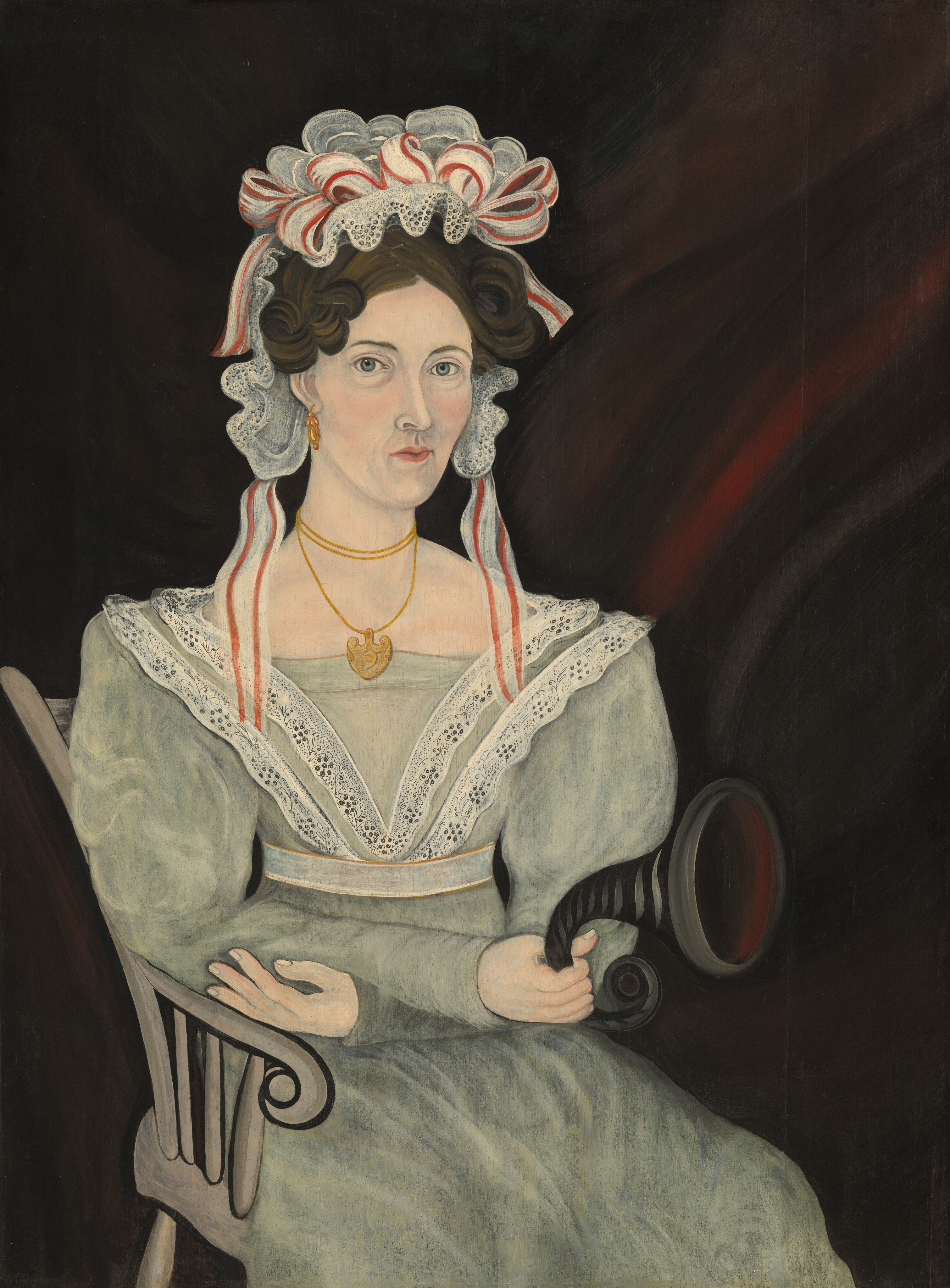 The image depicts a woman seated in a wooden chair, facing slightly to the right. She has light eyes, a straight nose, and a set expression. Her hair is dark brown, styled in soft curls under a white bonnet with red and white striped ribbons and lace trim. She wears a light green gown with a lace collar, two gold necklaces with a heart-shaped pendant, and holds a black object resembling an ear trumpet. The background is a dark brown with red undertones.