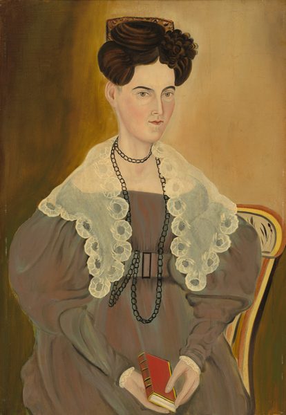 The image shows a portrait of a seated woman. She is sitting upright with her arms relaxed, holding a small red book. Her facial features are detailed, with a fair complexion, high cheekbones, and a slightly serious expression. Her dark hair is styled in an elaborate updo with a floral embellishment. The woman wears a formal, high-necked brown dress with voluminous sleeves, and a transparent lace-like cape draped over her shoulders. She has a long, black beaded necklace layered with a shorter one. The background is a muted, earthy tone with texture.