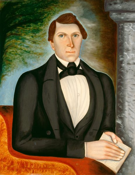 The image shows a man in a half-body portrait. He is seated, facing forward, with his torso and hands visible. His left arm rests on a surface. The man has angular features, light-colored eyes, brown hair styled to the side, and wears formal attire. He holds a book in his left hand. The background has a textured gradient with a pillar on the right and abstract greenery on the left.