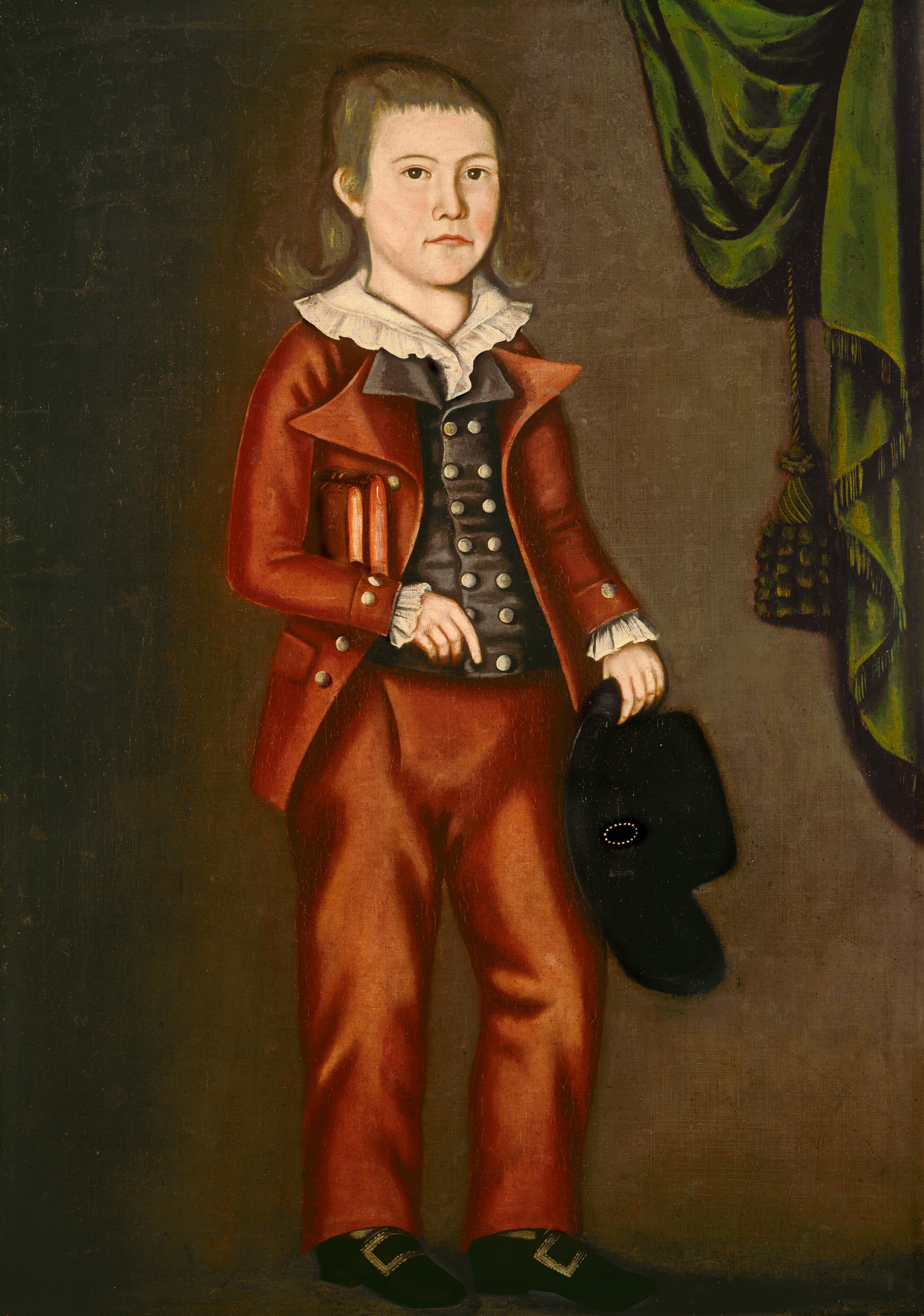 The image shows a full-body portrait of a young person with fair skin, wide eyes, and straight hair falling past the shoulders. They are wearing a formal outfit consisting of a red coat over a dark waistcoat with rounded buttons, white cuffs, and a white collar. The person holds a hat in their left hand and a stack of red books under their left arm, with their right arm resting against their side. In the background, there is a plain, muted color with a green drape with tassels visible to the right of the subject.